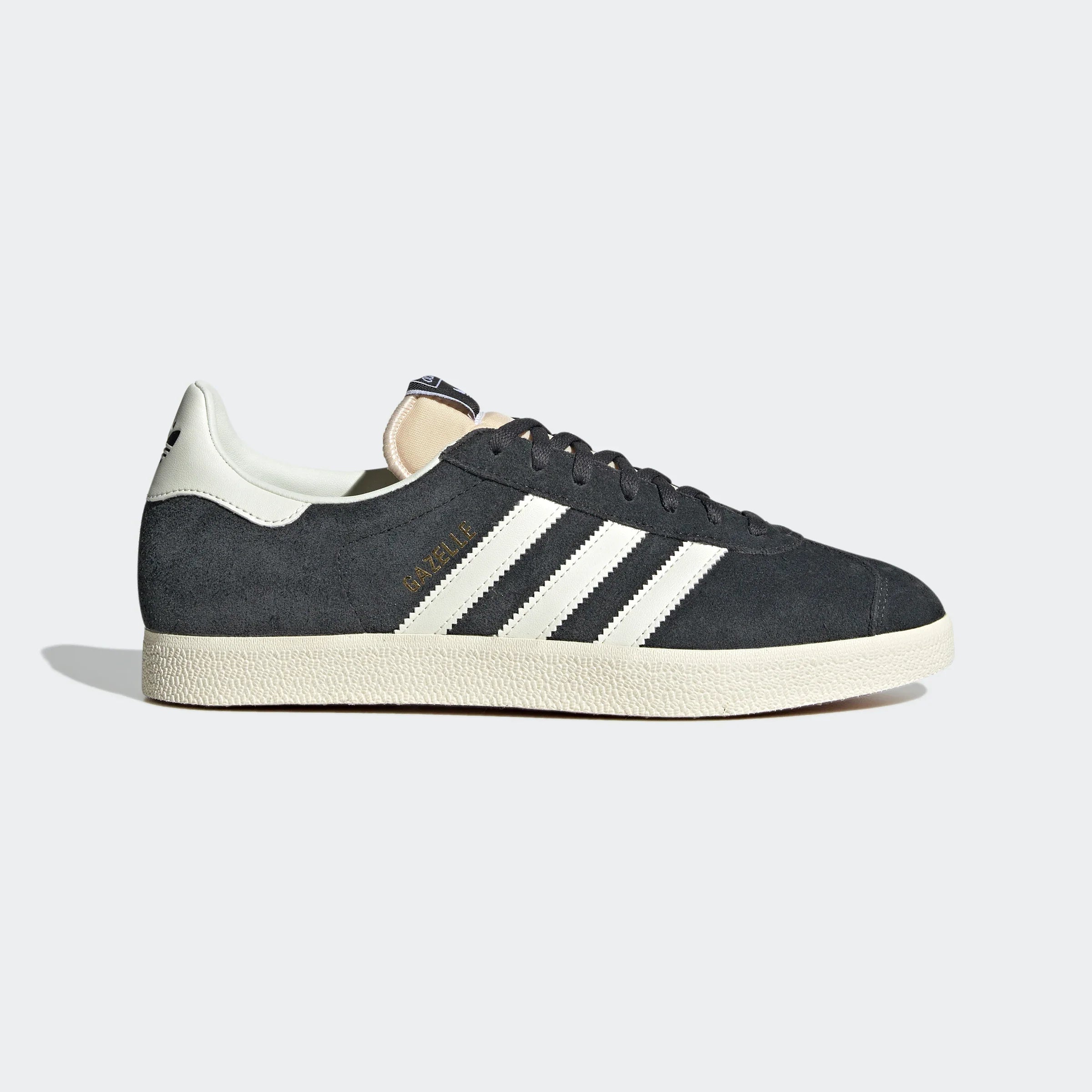 "Anthrazitfarbene Adidas Gazelle Schuhe mit off-weißen Streifen und cremefarbener Sohle. Klassisches Wildleder-Obermaterial, goldener 'Gazelle' Schriftzug an der Seite."