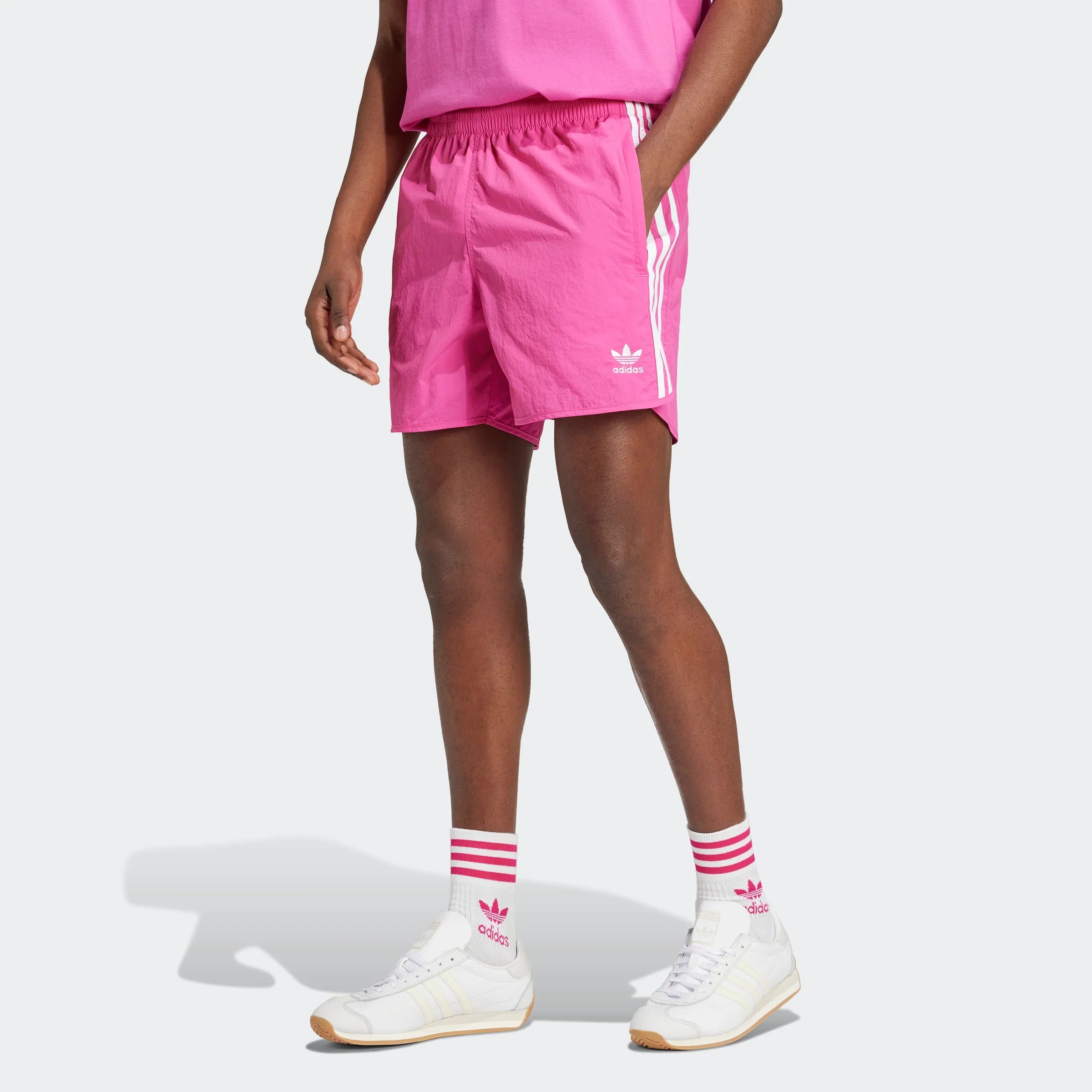 "Leuchtend pinke Adidas Sprinter Shorts. Kurze, sportliche Hose mit elastischem Bund und kleinem, farblich passendem Adidas Logo am Bein."