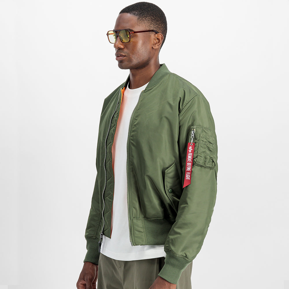 “Alpha Industries MA-1 (HERITAGE) Bomberjacke in Sage Green, aus robustem Nylon, mit orangefarbenem Innenfutter und ikonischem Ärmeltaschen-Design.“