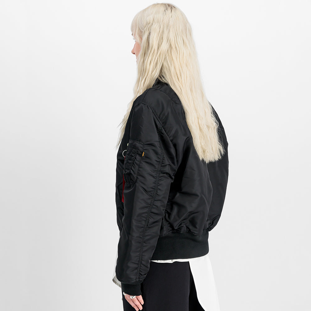 “Alpha Industries MA-1 (HERITAGE) Bomberjacke in Schwarz, aus robustem Nylon, mit ikonischem Flight-Tag am Ärmel und gestepptem orangenem Innenfutter.“