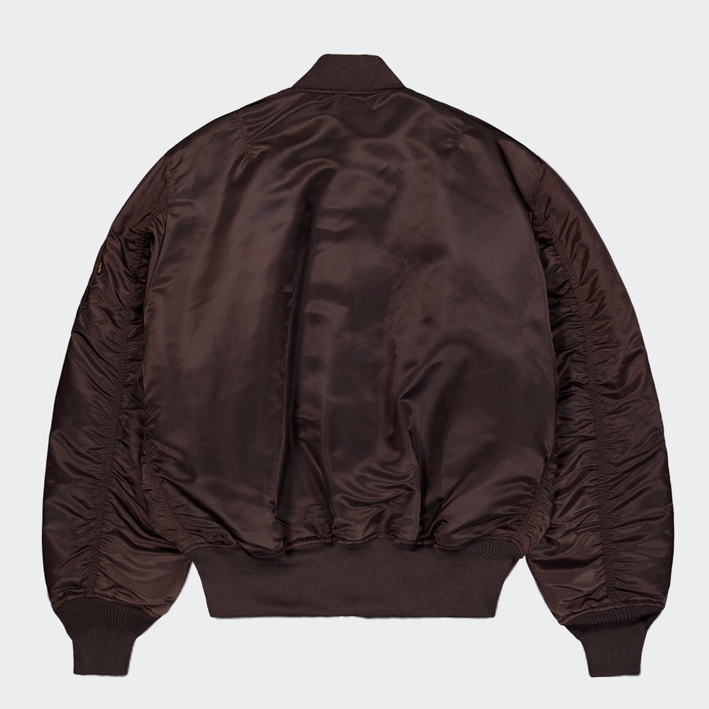 "Alpha Industries MA-1 (HERITAGE) Bomberjacke in Hunter Brown, aus strapazierfähigem Nylon, mit Rippbündchen und ikonischem Flight-Tag am Ärmel."