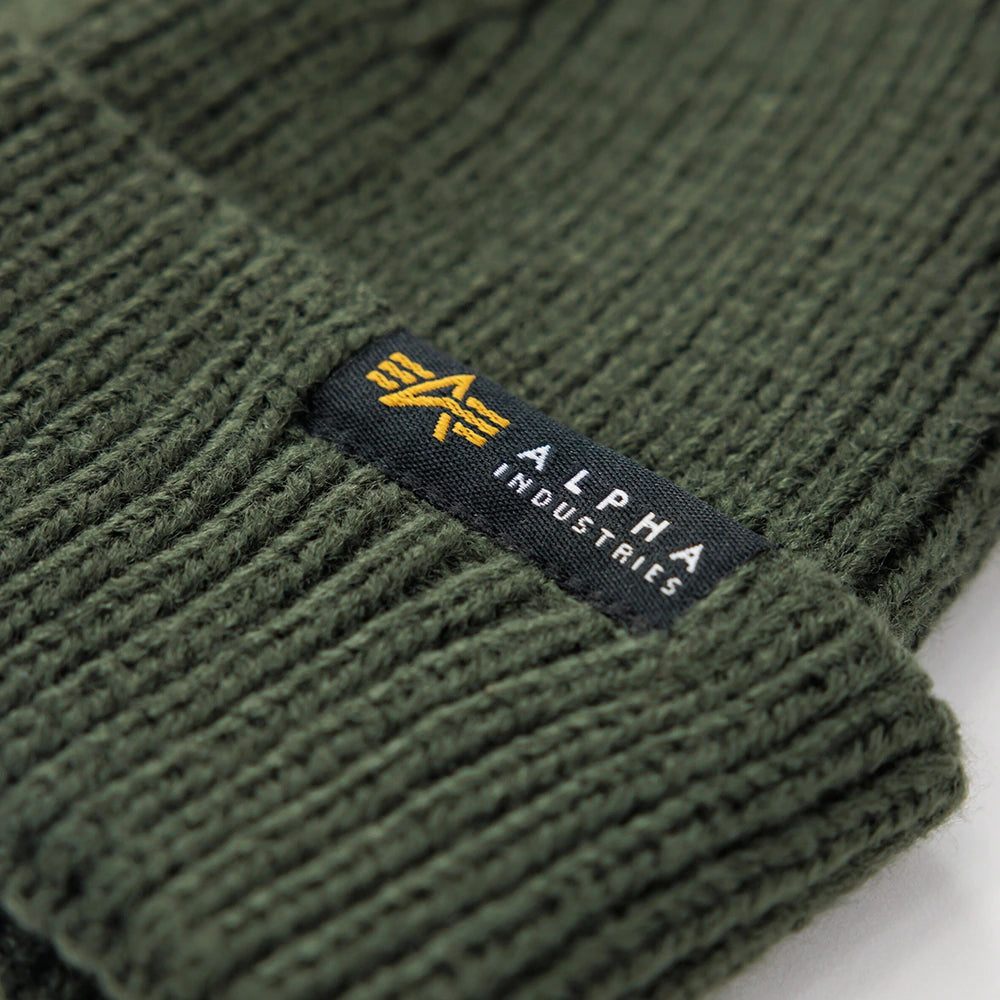 “Alpha Industries Dockers Beanie – Dark Olive. Olivgrüne Kurz-Beanie aus Acryl-Strick, mit Umschlag und kleinem Alpha Industries Logo-Label.“