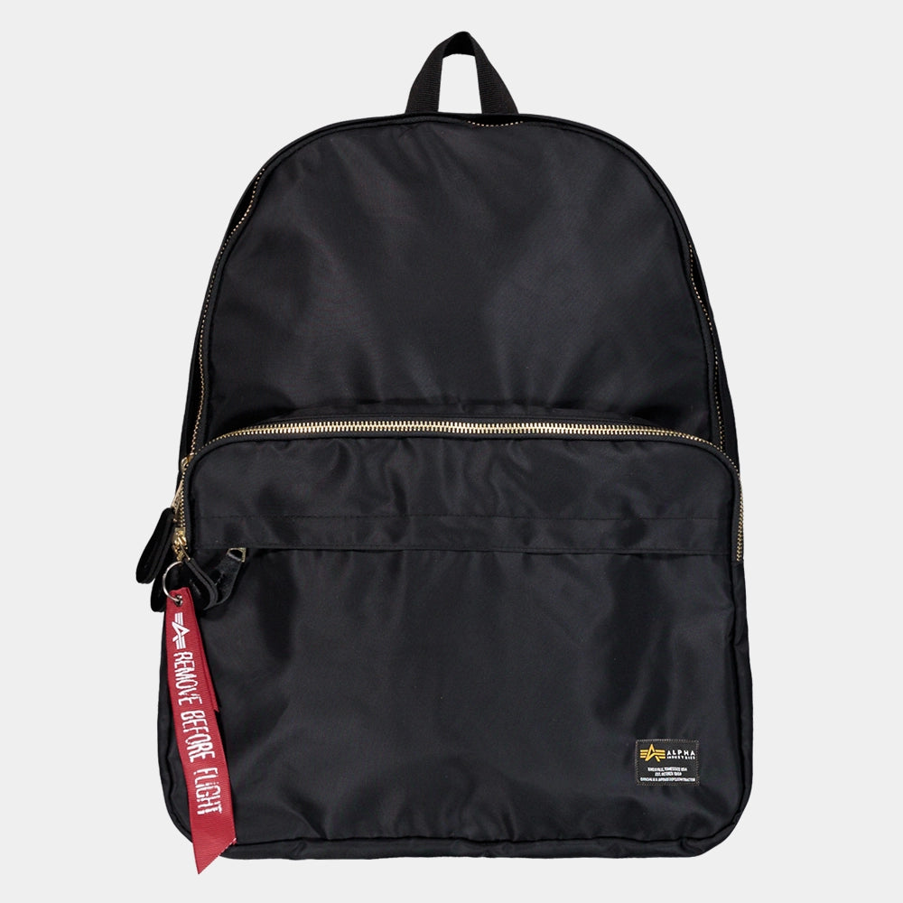 “Schwarzer Alpha Industries Crew Backpack aus strapazierfähigem Flight-Nylon mit rotem Remove Before Flight Anhänger und gepolsterten Trägern bei Stickabush Berlin.“