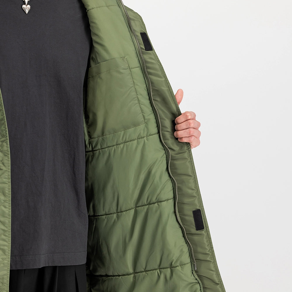 "Grüner Winterparka aus Nylon von Alpha Industries mit einem auffälligen Print auf dem Rücken und einer Teddyfutter-Kapuze bei Stickabush Berlin.“