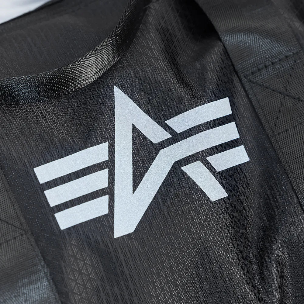 “Schwarze Alpha Industries Sporttasche aus Ripstop-Gewebe mit rotem Remove Before Flight Anhänger und stabilen Kordelzügen bei Stickabush Berlin.“