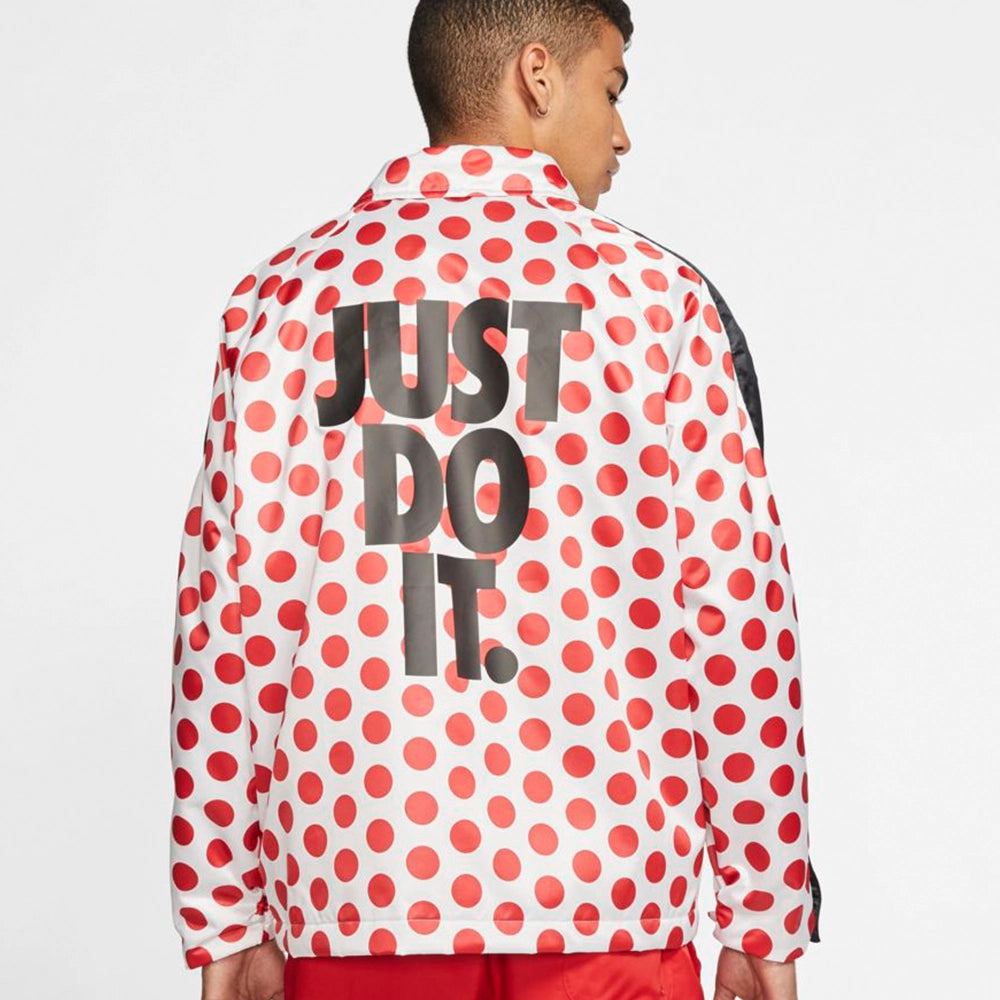 “Weiße Nike Winterjacke mit schwarzen Punkten (Polka Dots), schwarze Druckverschluss und großem Just Do It Schriftzug auf dem Rücken bei Stickabush Berlin.“