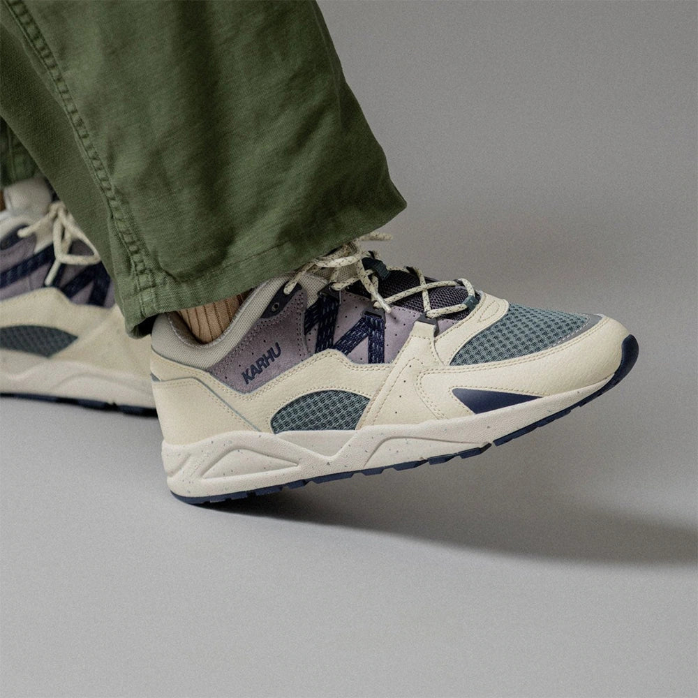 „Der Karhu Fusion 2.0 Herren Sneaker in Beige/Blaugrau/Lila (Naval Academy / Solitary Star) mit reflektierenden Details und praktischer Zuglasche und einer beigen Sohle bei Stickabush Berlin.“