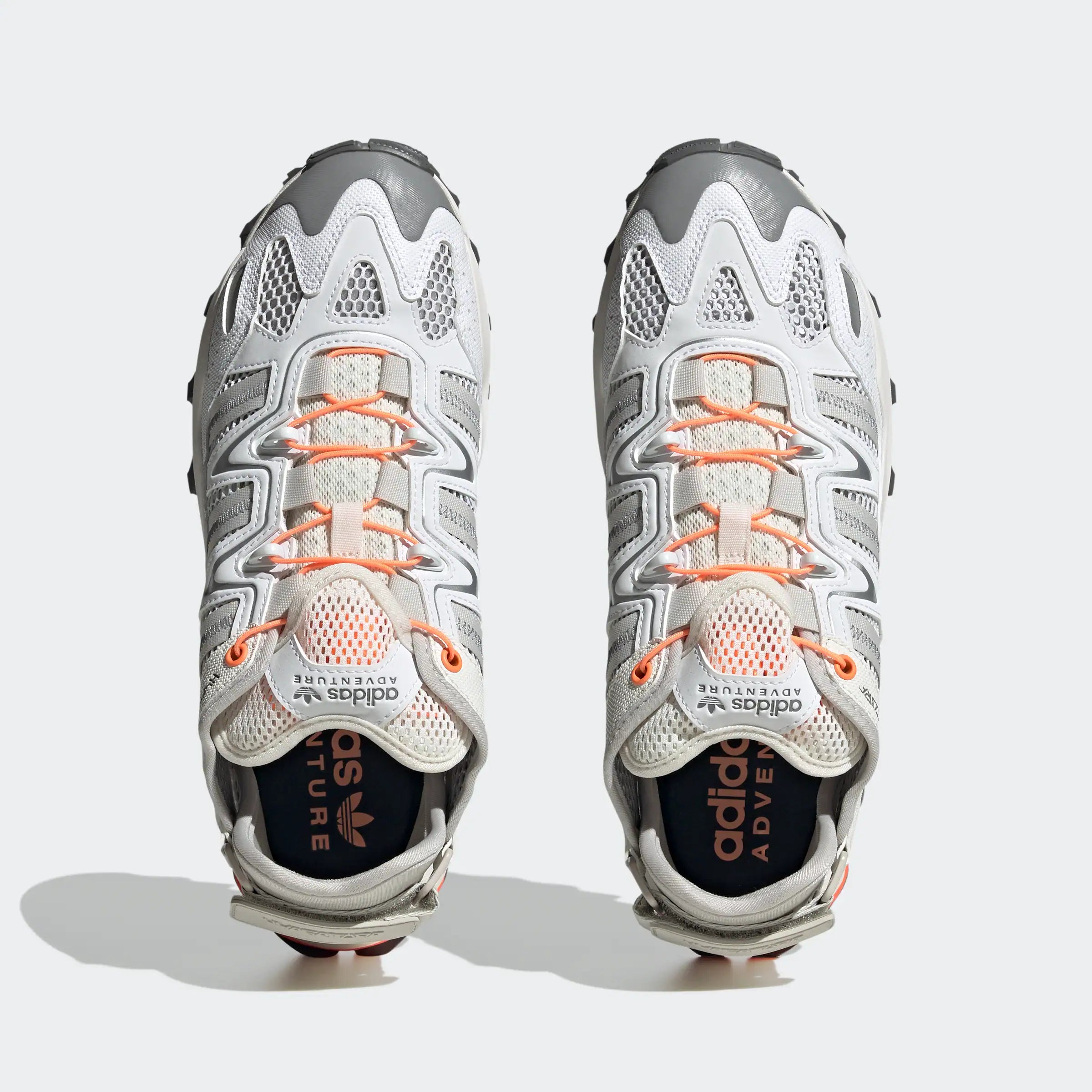“Weiße ("Footwear White") Adidas Hyperturf Sneaker mit grauen und orangefarbenen Akzenten. Trail-inspirierte Schuhe aus Textil und Synthetik-Wildleder, mit Adiprene+-Dämpfung und markanter Außensohle.“