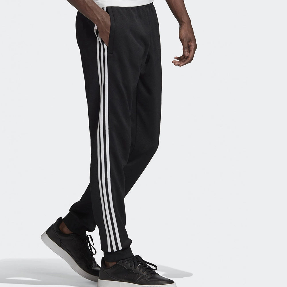 "Schwarze adidas Classics SST Trainingshose mit weißen 3-Streifen, Trefoil-Logo und schmal zulaufendem Bein bei Stickabush Berlin."