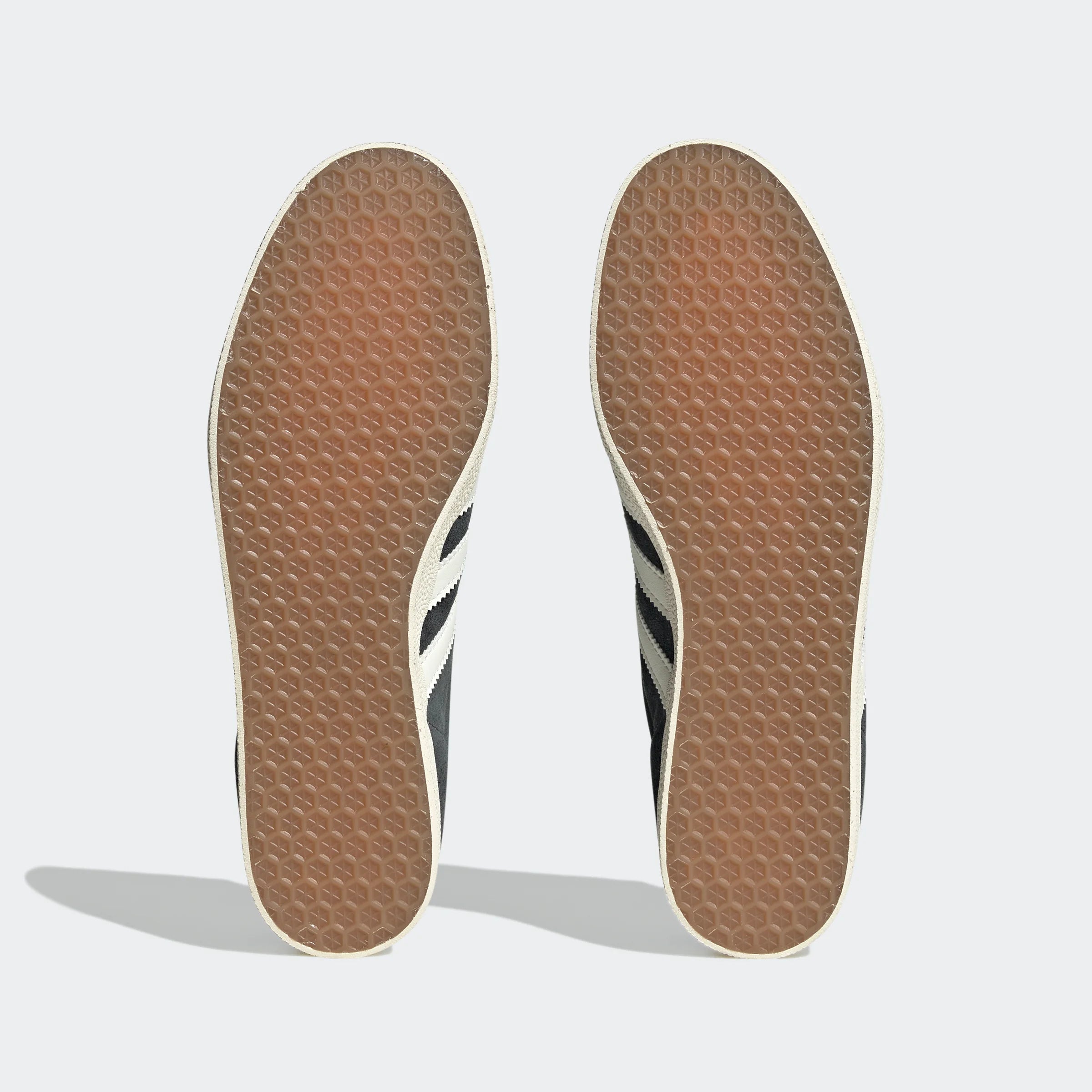"Anthrazitfarbene Adidas Gazelle Schuhe mit off-weißen Streifen und cremefarbener Sohle. Klassisches Wildleder-Obermaterial, goldener 'Gazelle' Schriftzug an der Seite."