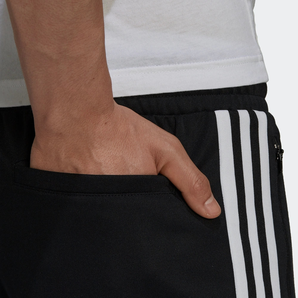 "Adidas Classics Beckenbauer Track Pants, Black, glattes Trikotmaterial (vermutlich Polyester), klassische Trainingshose mit drei weißen Streifen und Reißverschlusstaschen."
