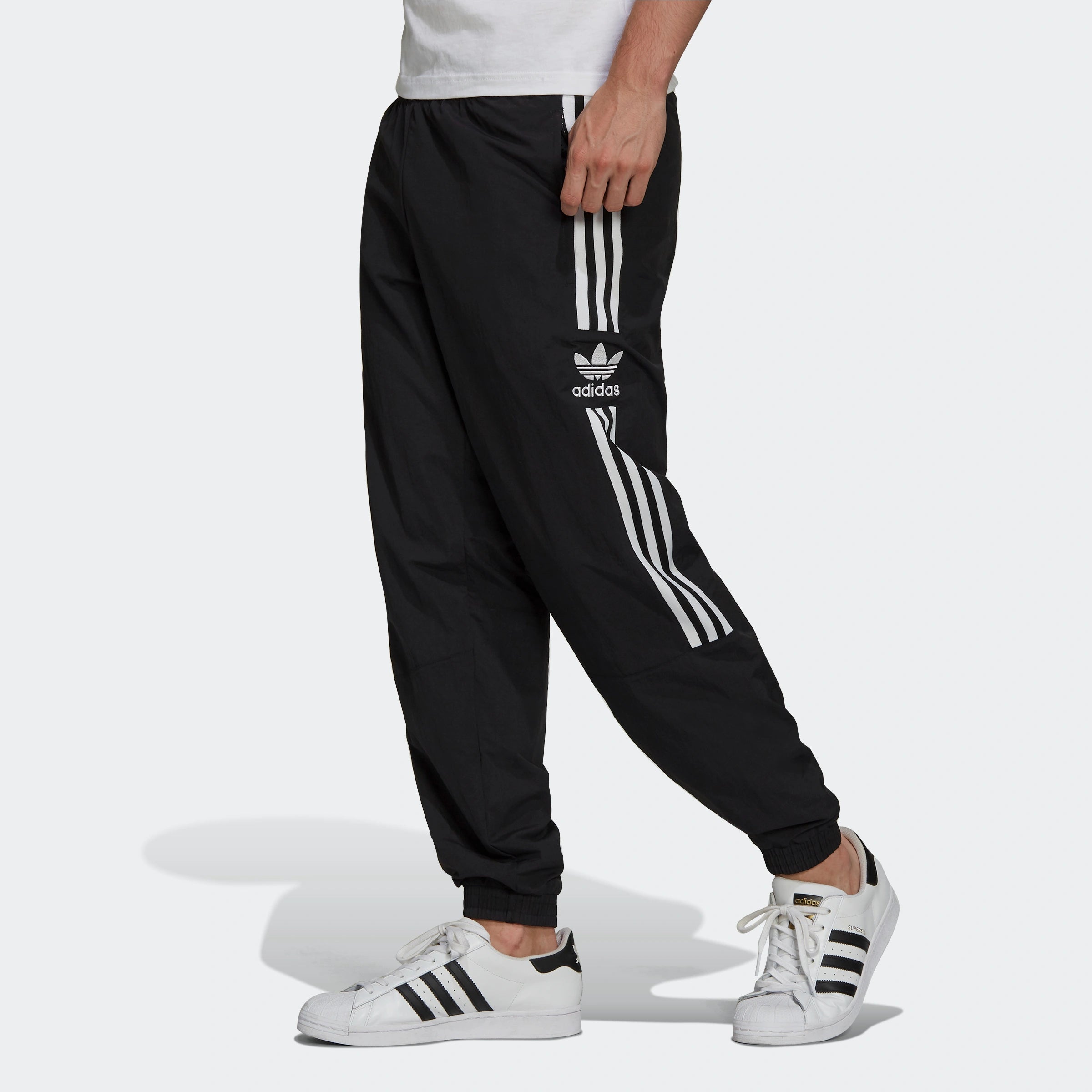 "Schwarze Adidas Trainingshose mit weißen seitlichen Streifen und weißem Trefoil-Logo am Bein. Klassischer Schnitt mit elastischem Bund und Bündchen."