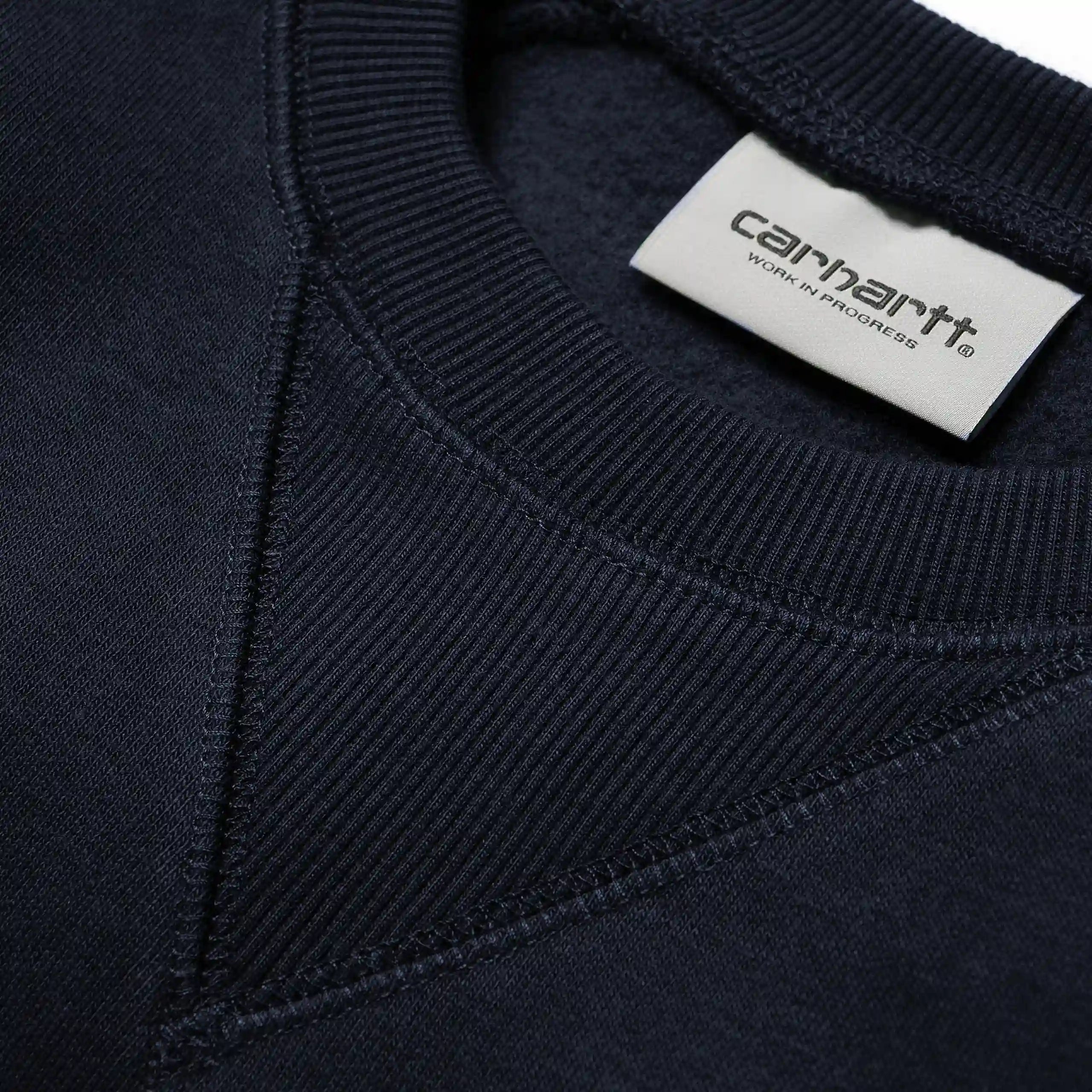 „Dunkelblaues Carhartt WIP Chase Sweatshirt mit goldenem Carhartt C-Logo-Stitch am Ärmel und Rundhalsausschnitt bei Stickabush Berlin."