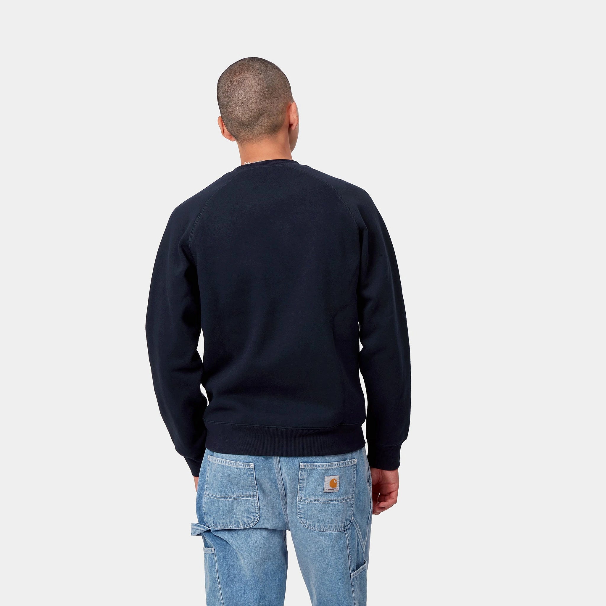 „Dunkelblaues Carhartt WIP Chase Sweatshirt mit goldenem Carhartt C-Logo-Stitch am Ärmel und Rundhalsausschnitt bei Stickabush Berlin."