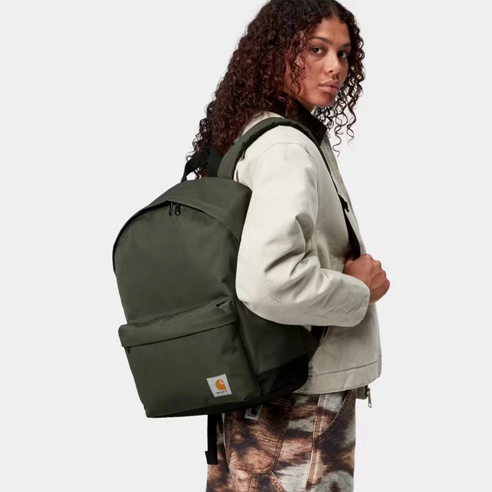 “Dunkelgrüner Carhartt WIP Jake Backpack (Opuntia) mit Reißverschluss-Fronttasche und dem typischen quadratischen Logo-Label bei Stickabush Berlin.“