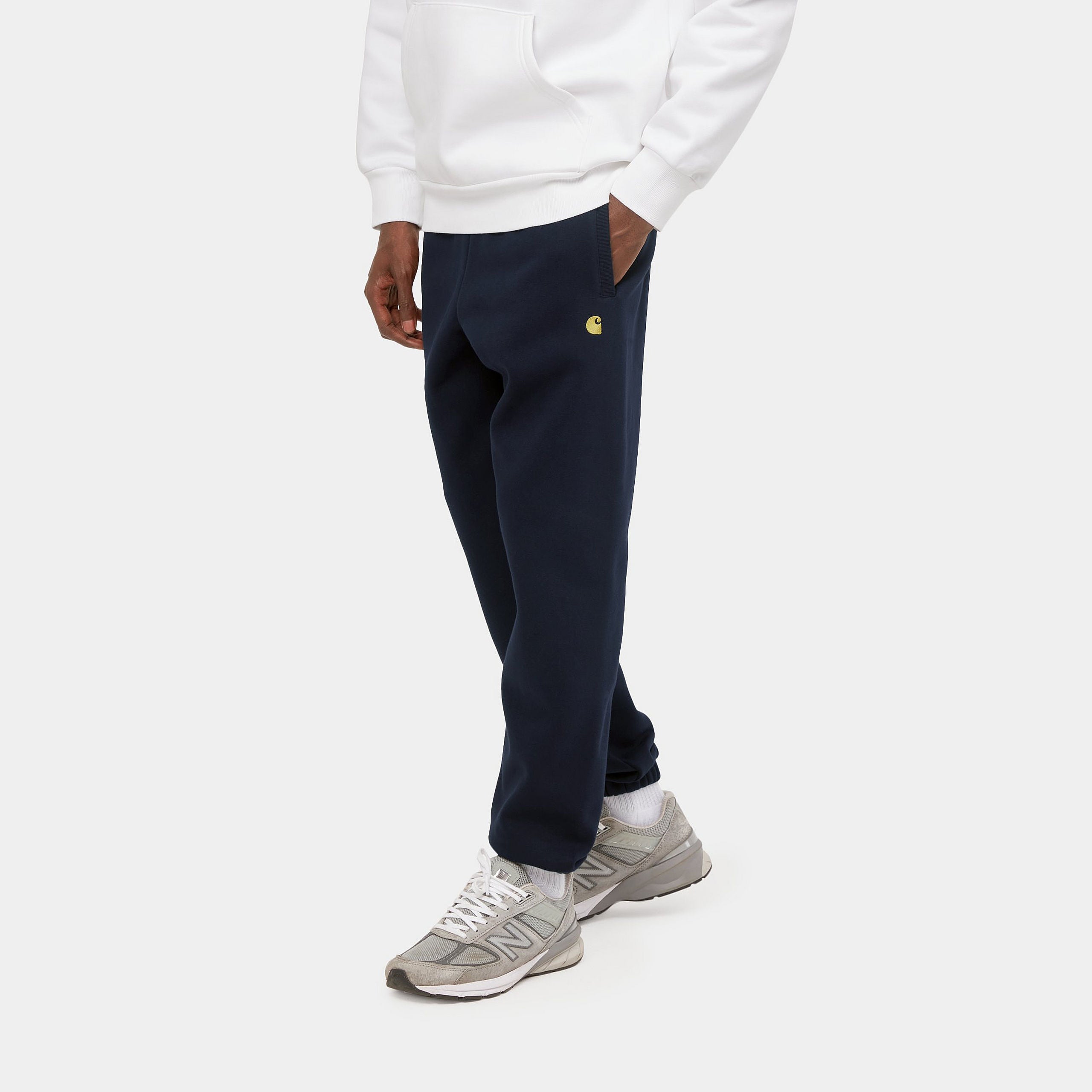 "Carhartt Chase Sweat Pant in Dunkelblau/Gold, Baumwollmischung, elastischer Bund, goldene Logo-Stickerei."