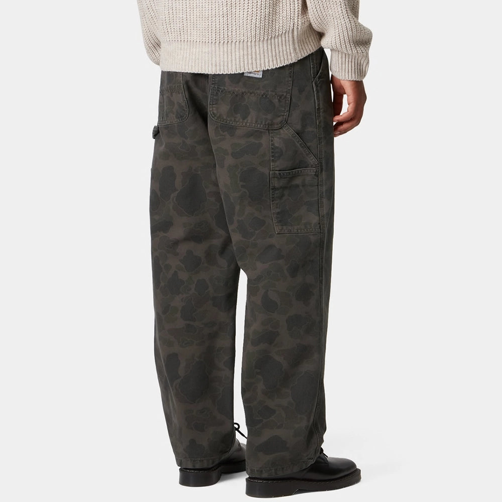 “Carhartt WIP Duck Single Knee Pant in Camo Duck. Robuste Workwear Canvas-Hose in Grün/Porphyr-Färbung mit Werkzeugtaschen und Hammerschlaufe.“