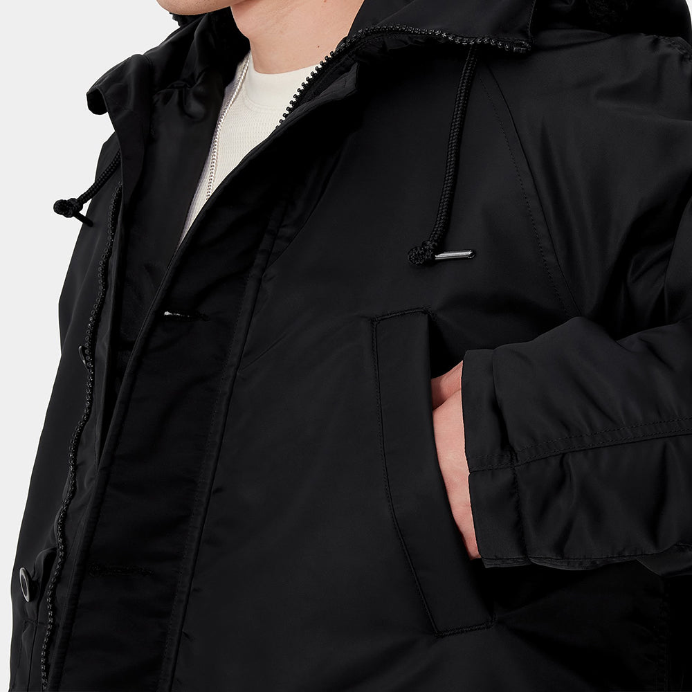 Carhartt WIP Hooded Olten Parka in Schwarz, getragen von einem Model, mit Kapuze und langen Ärmeln, aus robustem Canvas-Material.