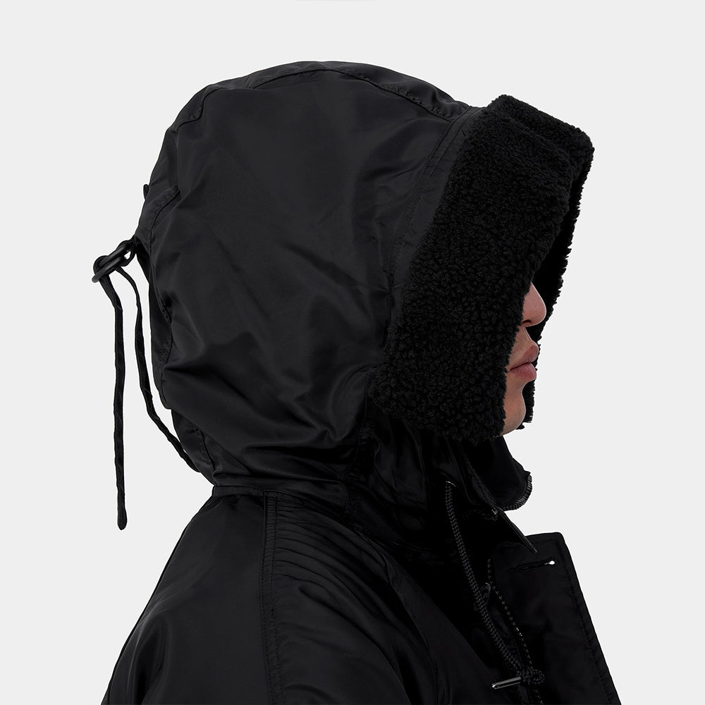 Carhartt WIP Hooded Olten Parka in Schwarz, getragen von einem Model, mit Kapuze und langen Ärmeln, aus robustem Canvas-Material.