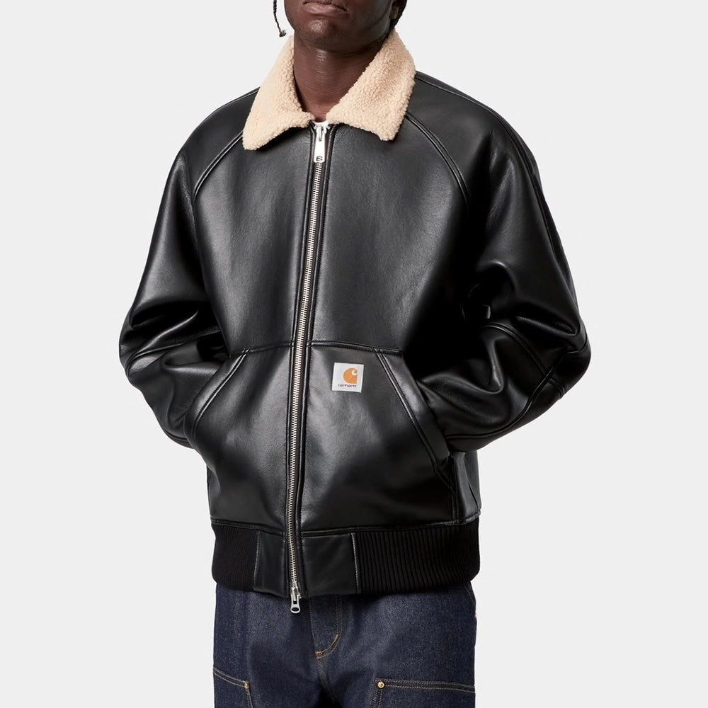 „Carhartt WIP Shepton Jacket in Schwarz/Natur, aus Kunstleder und warmem Fleece, mit Kontrastärmeln, Frontzipper und praktischen Taschen.“