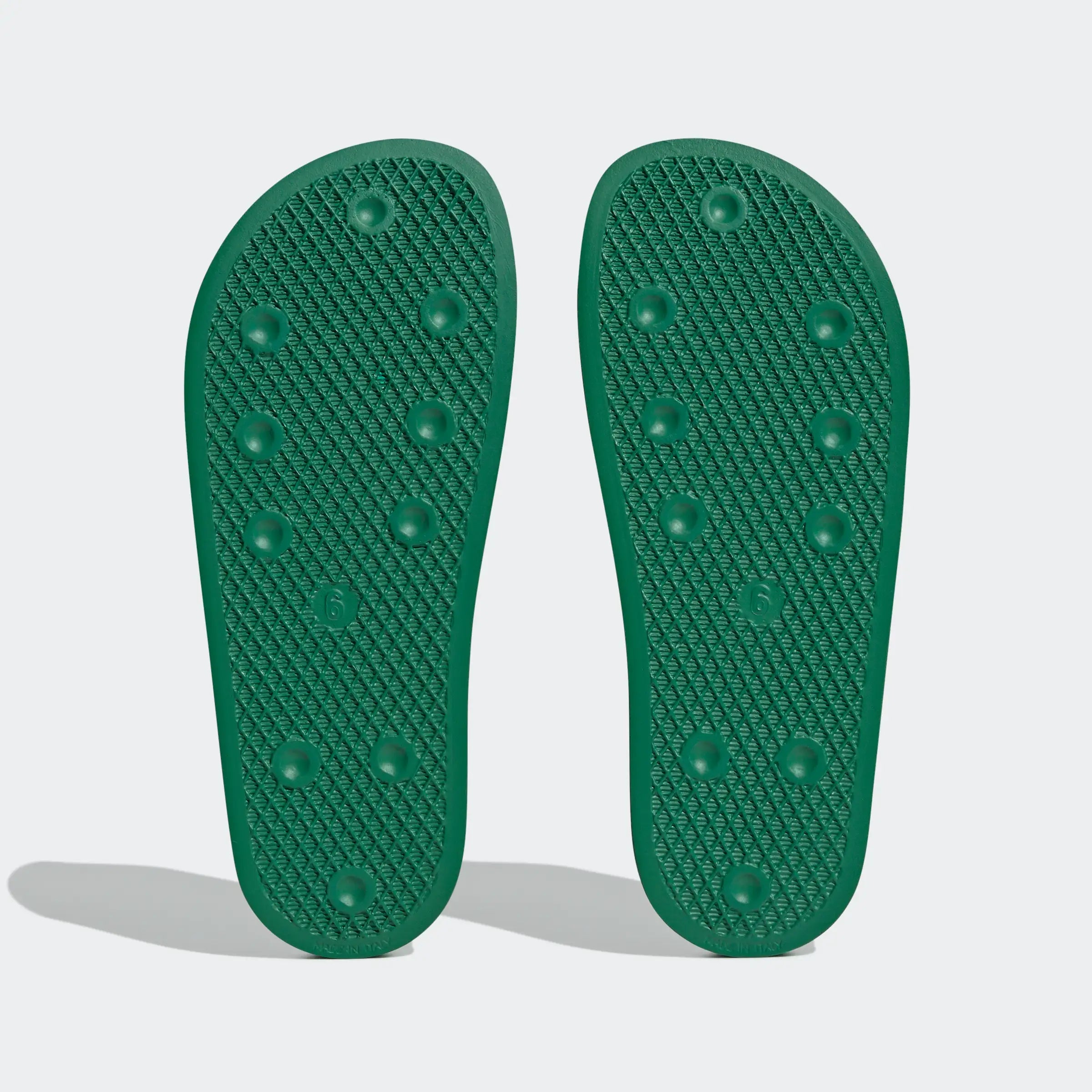 "Grüne Adidas Adilette für Damen mit weißen Details. Klassische Badesandale mit breitem Riemen und weißem Adidas Logo. Bequemes, leichtes Material."