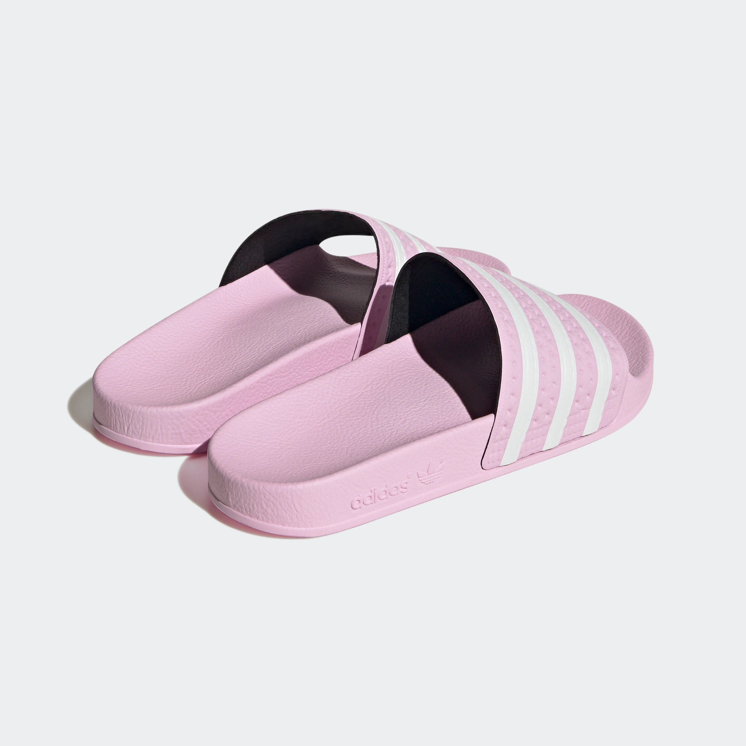 "Rosafarbene Adidas Adilette für Damen mit weißen Details. Klassische Badesandale mit breitem Riemen und weißem Adidas Logo. Bequemes, leichtes Material."