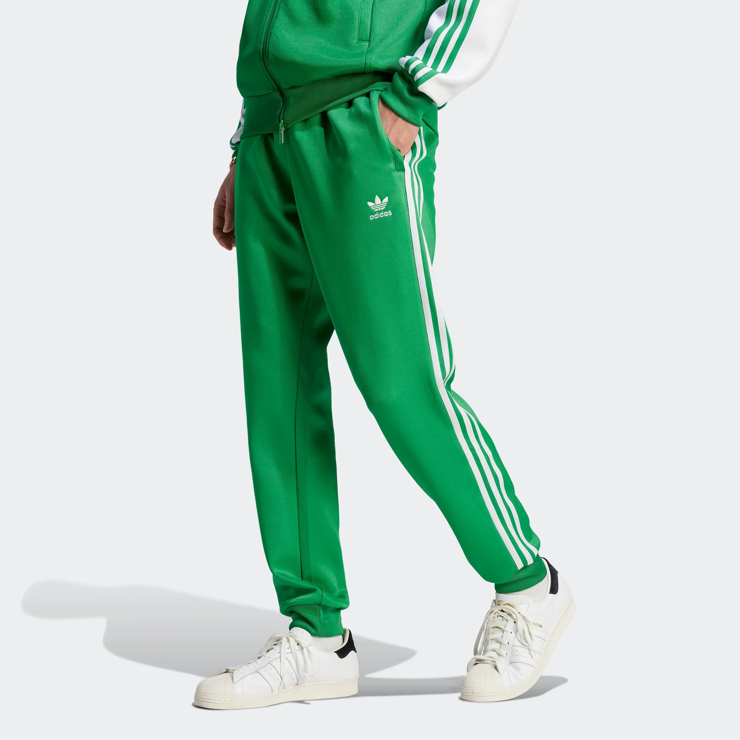 "Adidas Classics SST Trainingshose, Grün, glattes Trikotmaterial (vermutlich Polyester), klassische Trainingshose mit drei weißen Streifen an den Seiten."