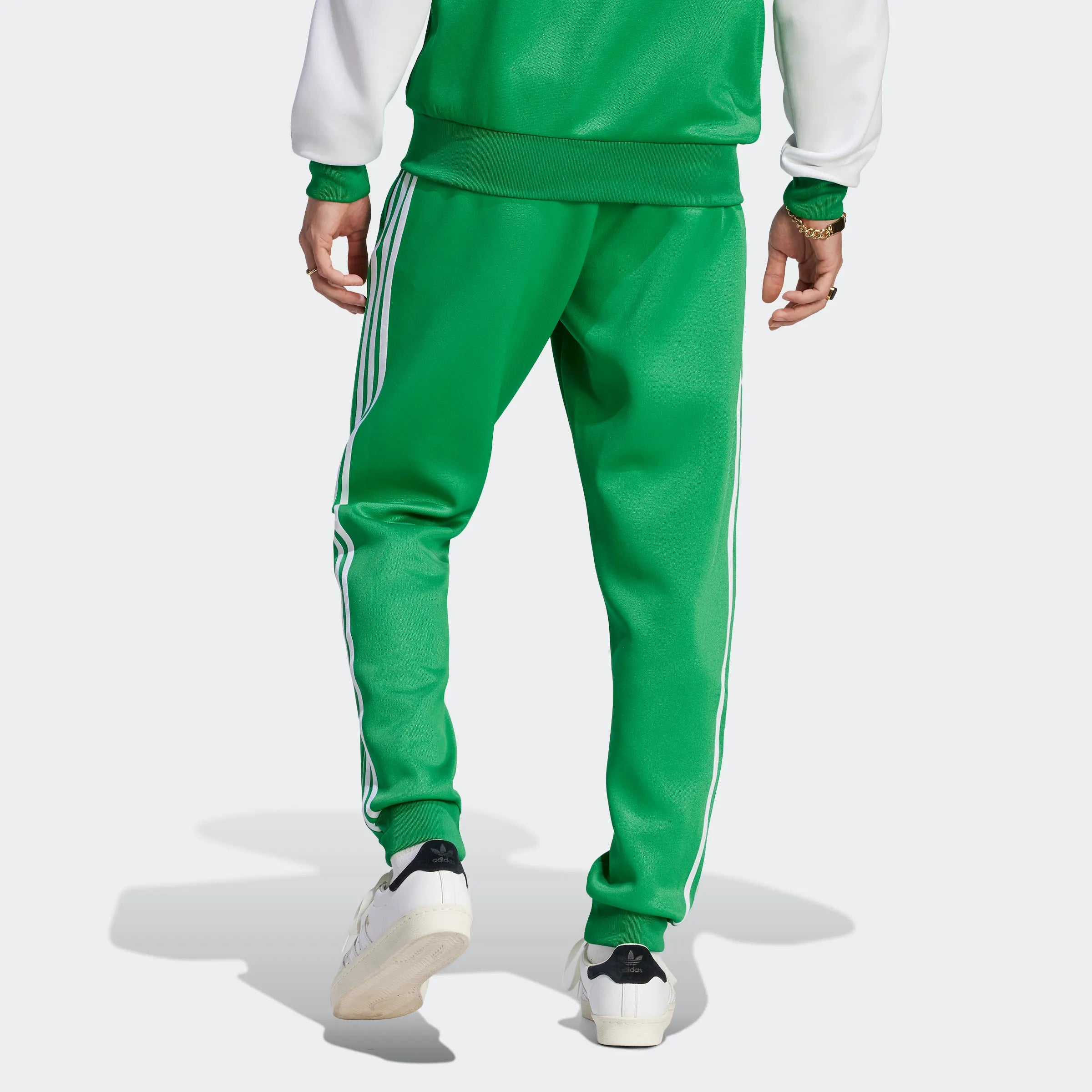 "Adidas Classics SST Trainingshose, Grün, glattes Trikotmaterial (vermutlich Polyester), klassische Trainingshose mit drei weißen Streifen an den Seiten."