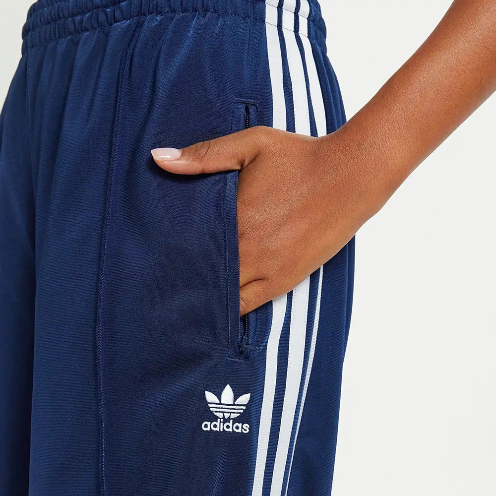 “Adidas Firebird Track Pants Loose Fit W in Dunkelblau. Lockere Hose aus glänzendem Trikotstoff, mit weißen 3-Streifen und gesticktem Logo.“