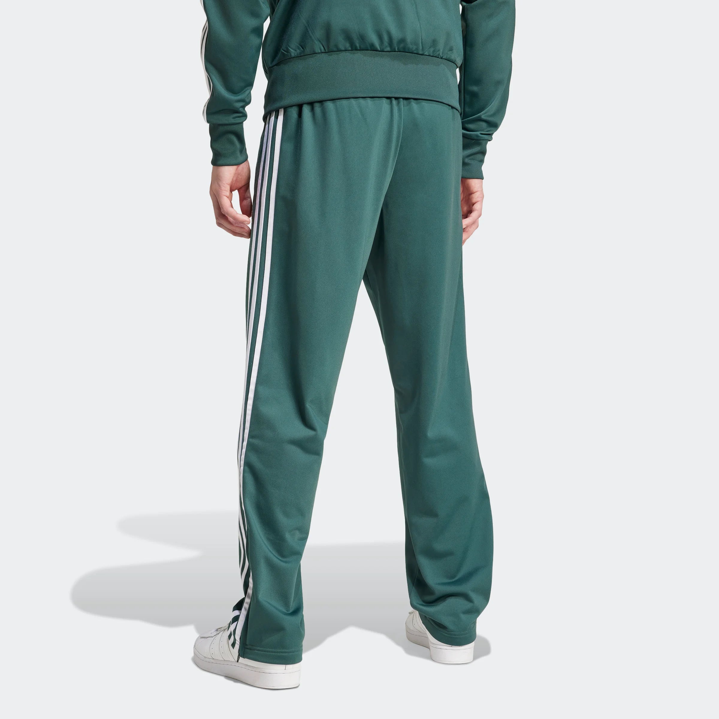 "Adidas Firebird Track Pants in Mineral Green/Weiß, Polyester, klassische Trainingshose mit weißen Streifen, grüne Farbe."