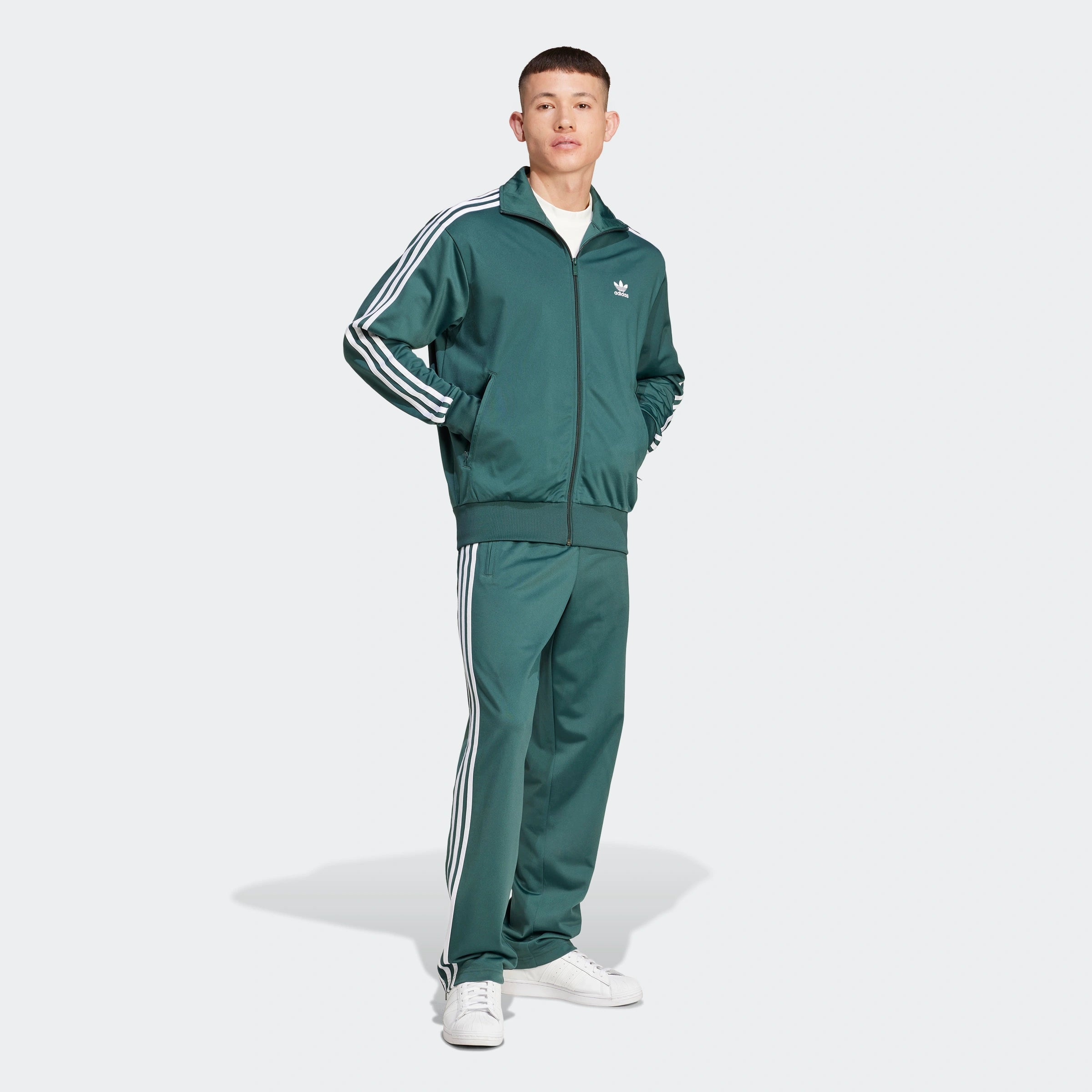 "Adidas Firebird Track Pants in Mineral Green/Weiß, Polyester, klassische Trainingshose mit weißen Streifen, grüne Farbe."