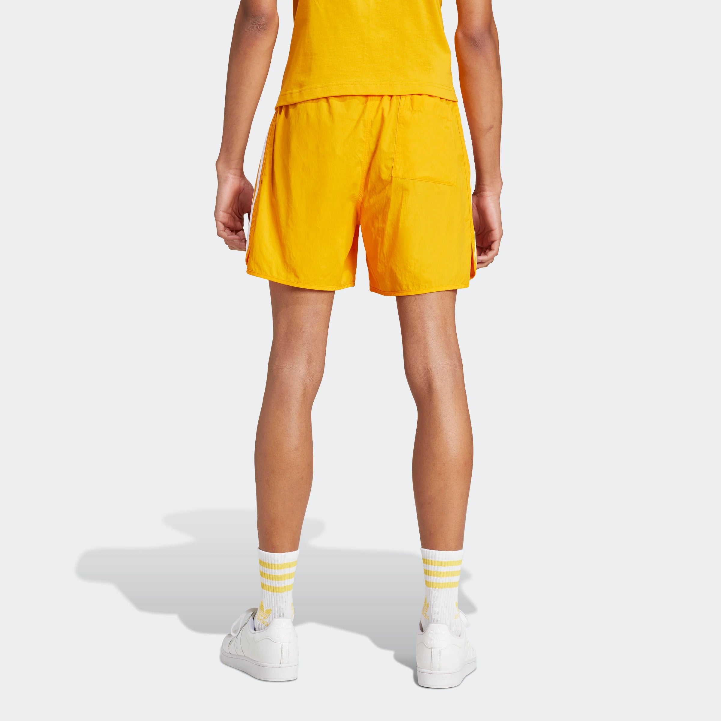 "Leuchtend orangefarbene Adidas Sprinter Shorts. Kurze, sportliche Hose mit elastischem Bund und kleinem, farblich passendem Adidas Logo am Bein."