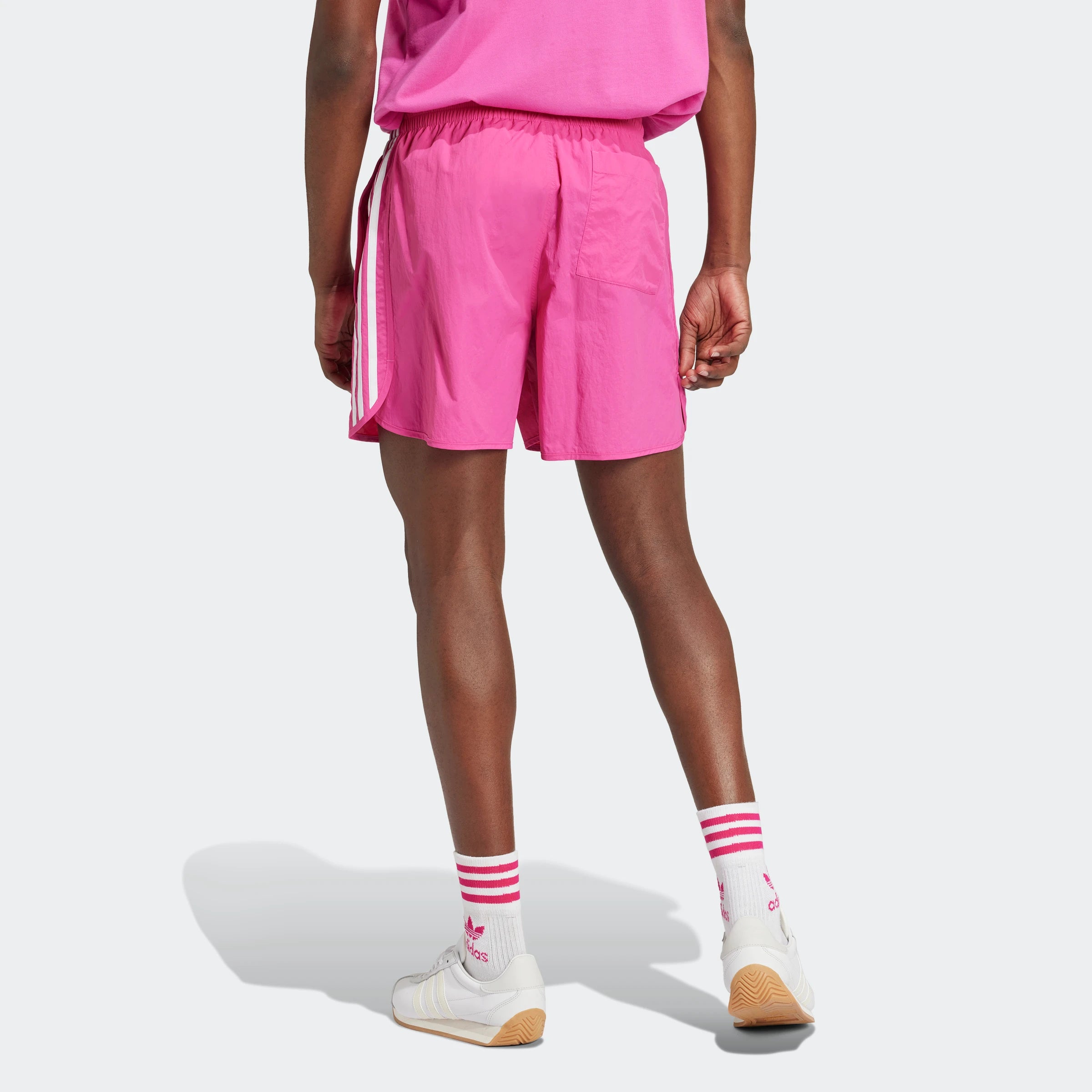 "Leuchtend pinke Adidas Sprinter Shorts. Kurze, sportliche Hose mit elastischem Bund und kleinem, farblich passendem Adidas Logo am Bein."