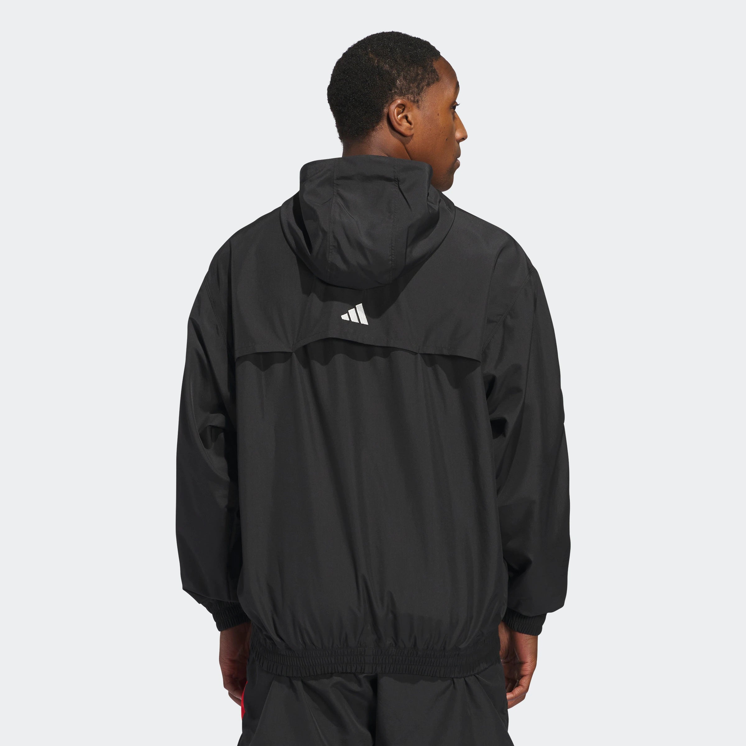 “Der Adidas Anthony Edwards Anorak Pullover in Schwarz, JC8782, verfügt über eine Kapuze mit drei auffälligen roten Diagonalstreifen auf der linken oberen Schulter, hlaben Reißverschluss und aus Polyester gefertigt.“