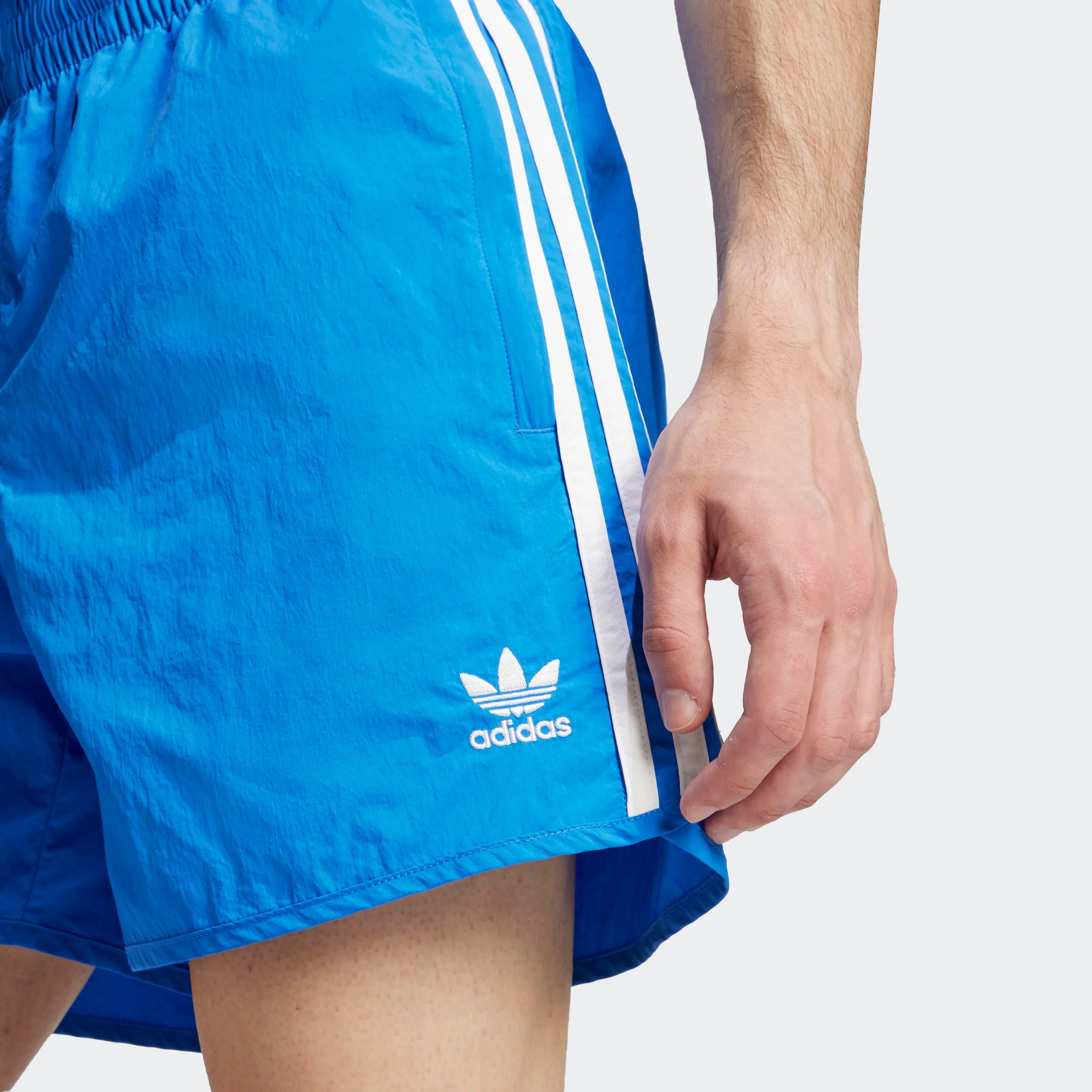 "Blaue Adidas Sprinter Shorts mit weißen seitlichen Streifen. Kurze, sportliche Hose mit elastischem Bund und kleinem Adidas Logo am Bein."