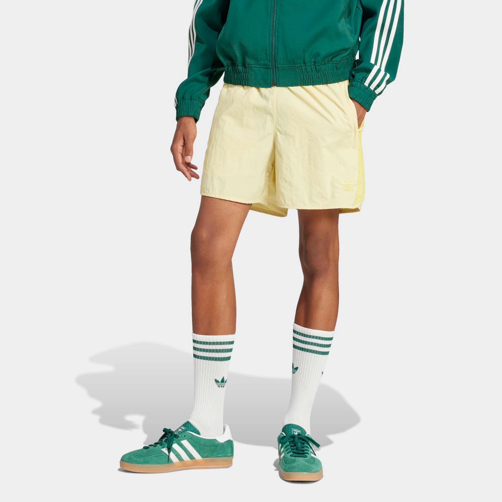 Adidas Classics Sprinter Shorts in einem hellen Gelb und mit gelben 3-Streifen und Trefoil-Logo, aus leichtem Material, von vorne abgebildet.