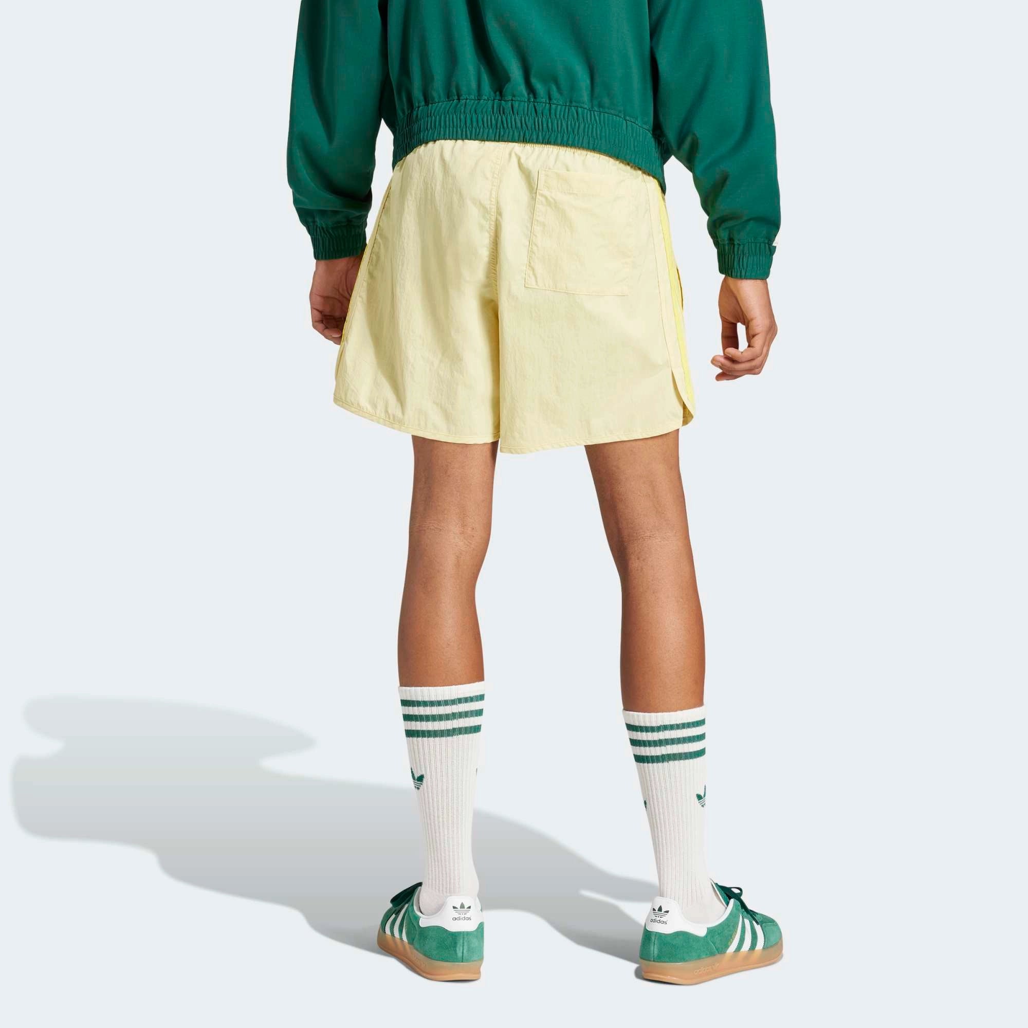 Adidas Classics Sprinter Shorts in einem hellen Gelb und mit gelben 3-Streifen und Trefoil-Logo, aus leichtem Material, von vorne abgebildet.