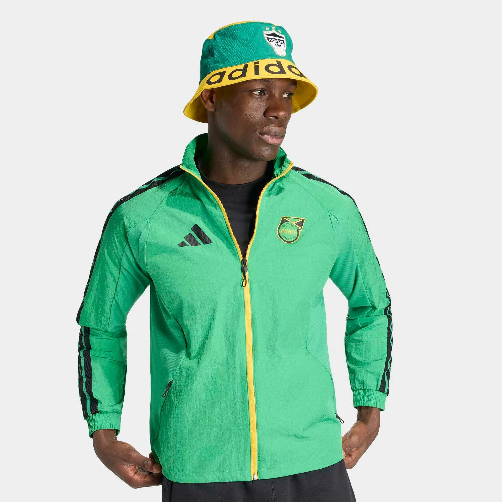 “Adidas Originals Jamaica Home Anthem Jacket in Vivid Green mit gelb-schwarzen Details und dem Logo des jamaikanischen Fußballverbandes bei Stickabush Berlin.“