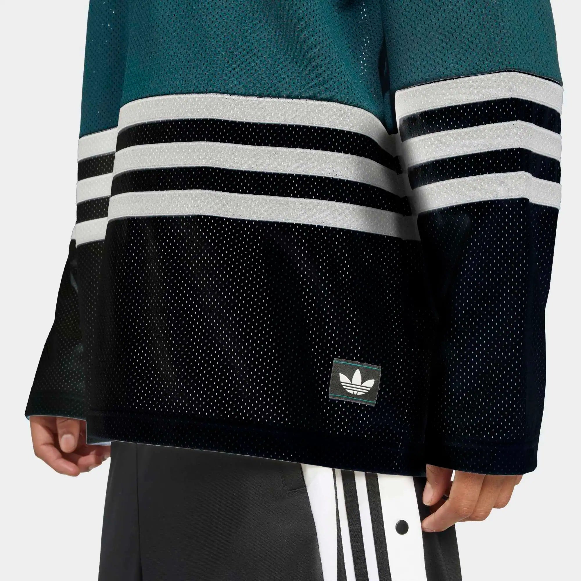 "Grünes adidas Originals Hockey Jersey (Aurora Ivy) mit V-Ausschnitt, weißen Kontraststreifen und Trefoil-Logo auf der Brust bei Stickabush Berlin."