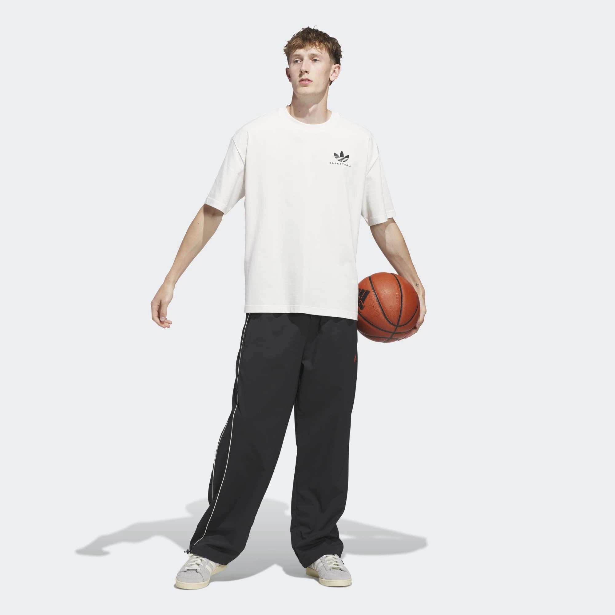 „Frontansicht Outfit mit Bball des Adidas Originals Worldwide Hoops GFX Tee in Cloud White – Weißes Baumwoll-T-Shirt mit schwarzem Basketball-Grafikprint bei Stickabush Berlin.“