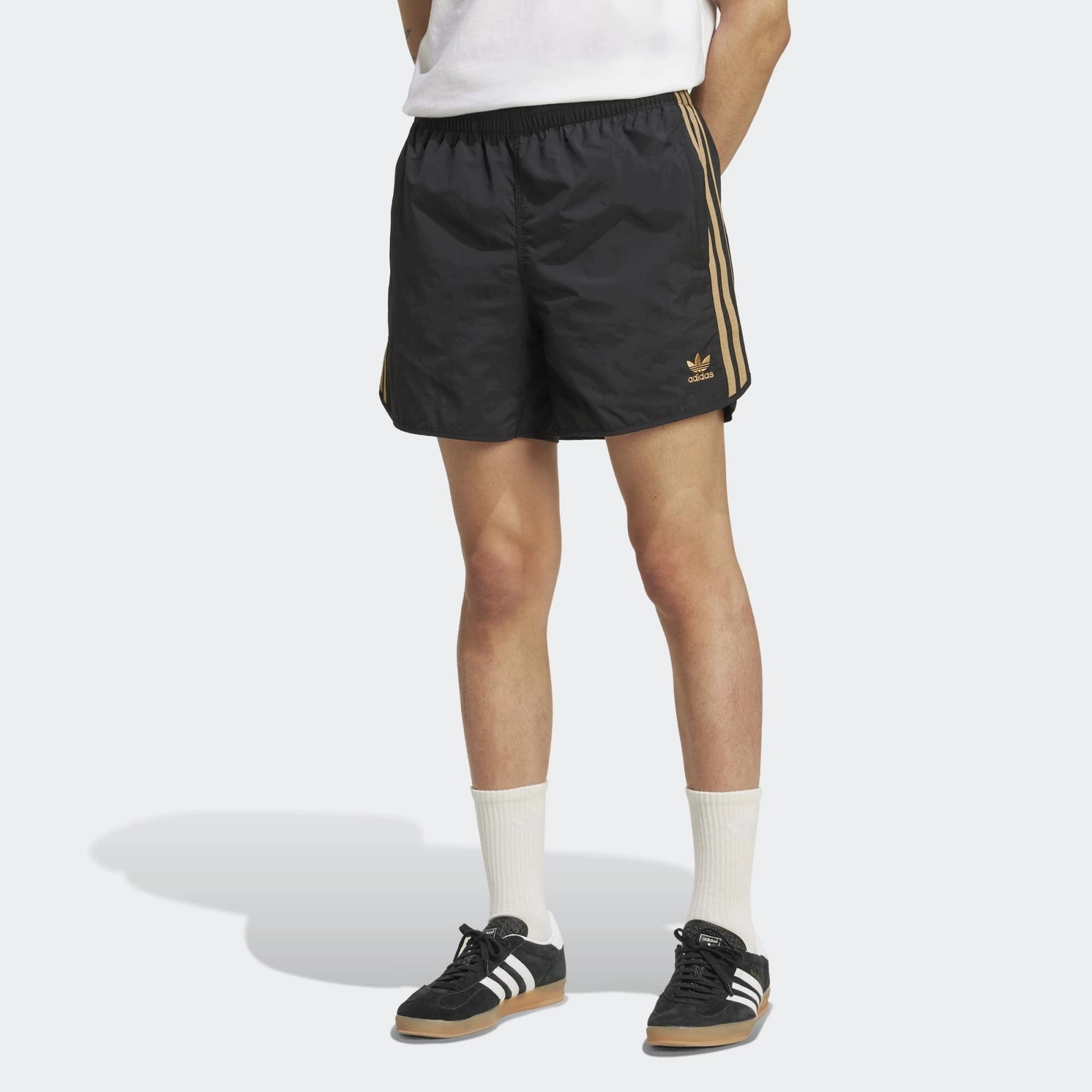 Adidas Classics Sprinter Shorts. Kurze, schwarze Shorts aus recyceltem Polyester, mit elastischem Bund, drei braunen Seitenstreifen und gesticktem Trefoil-Logo.