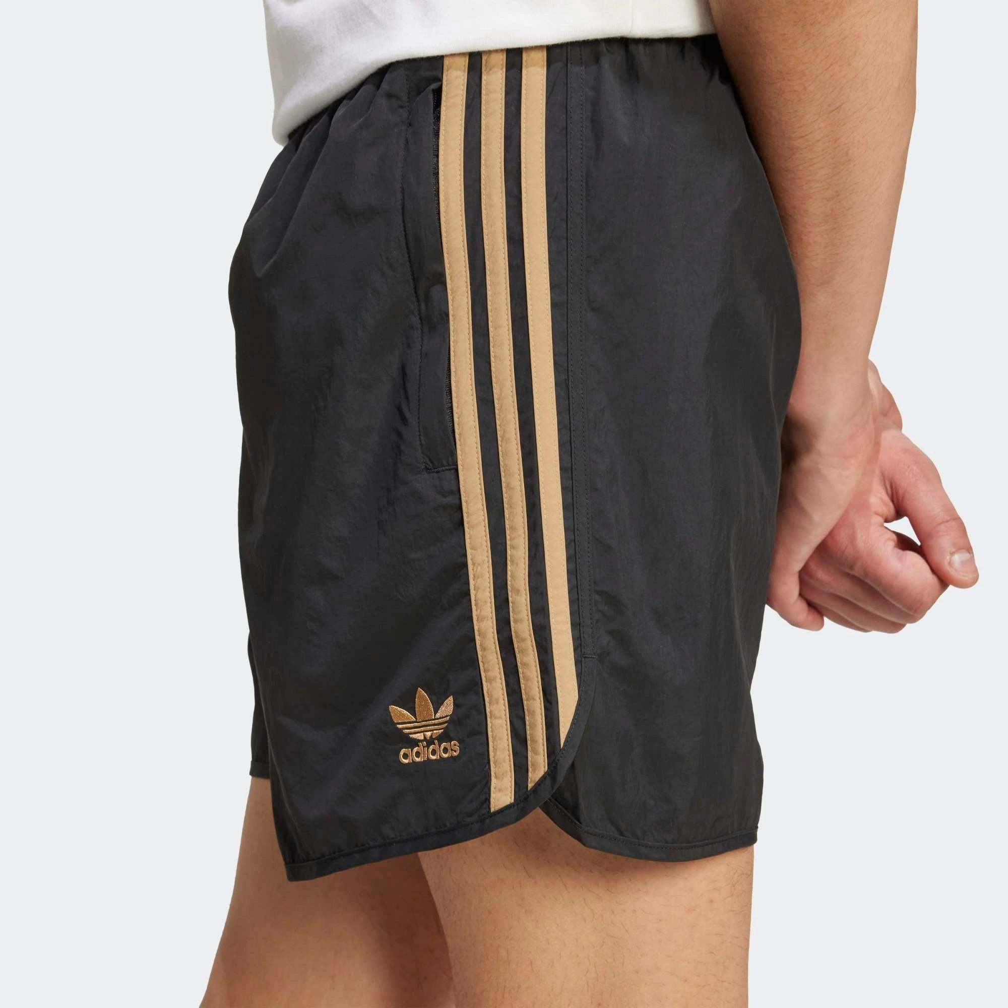 Adidas Classics Sprinter Shorts. Kurze, schwarze Shorts aus recyceltem Polyester, mit elastischem Bund, drei braunen Seitenstreifen und gesticktem Trefoil-Logo.