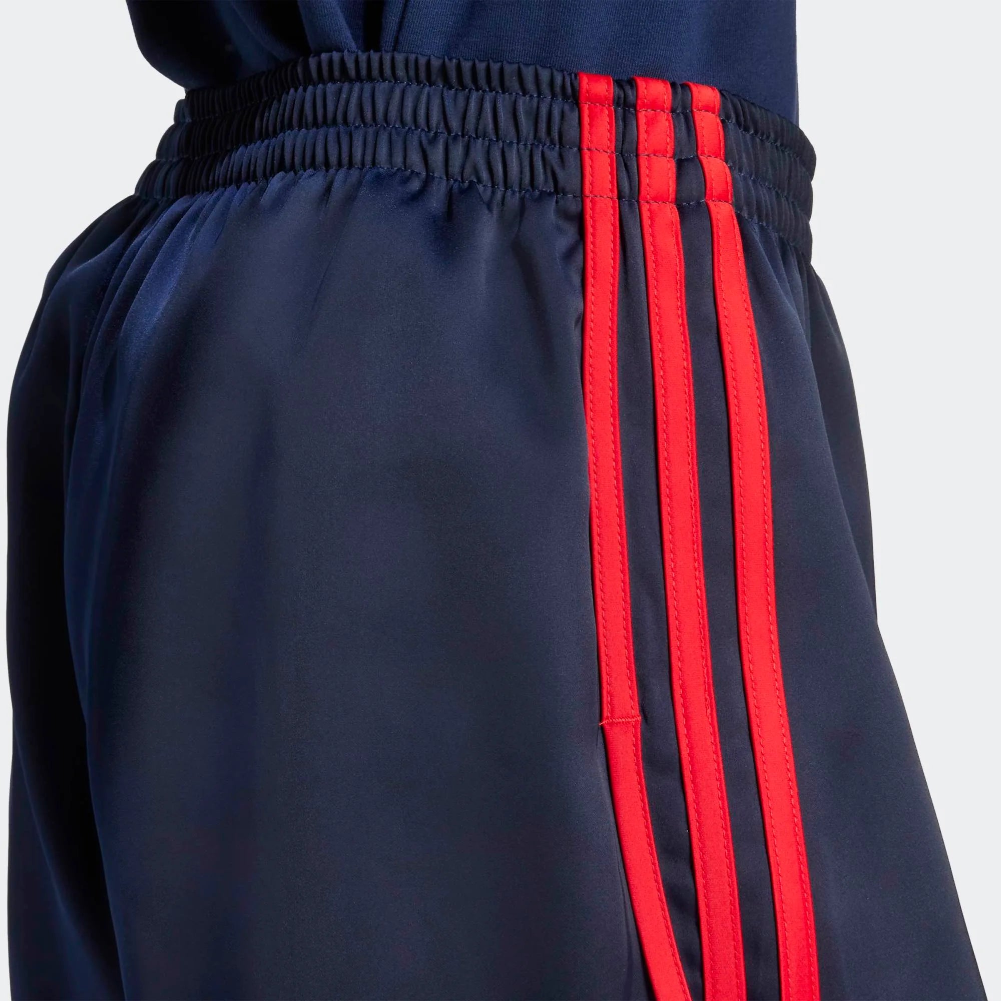 Adidas 3-Stripes Sprinter Shorts in Dunkelblau. Hergestellt aus recyceltem Polyester, mit leuchtend roten 3-Streifen an den Seiten.