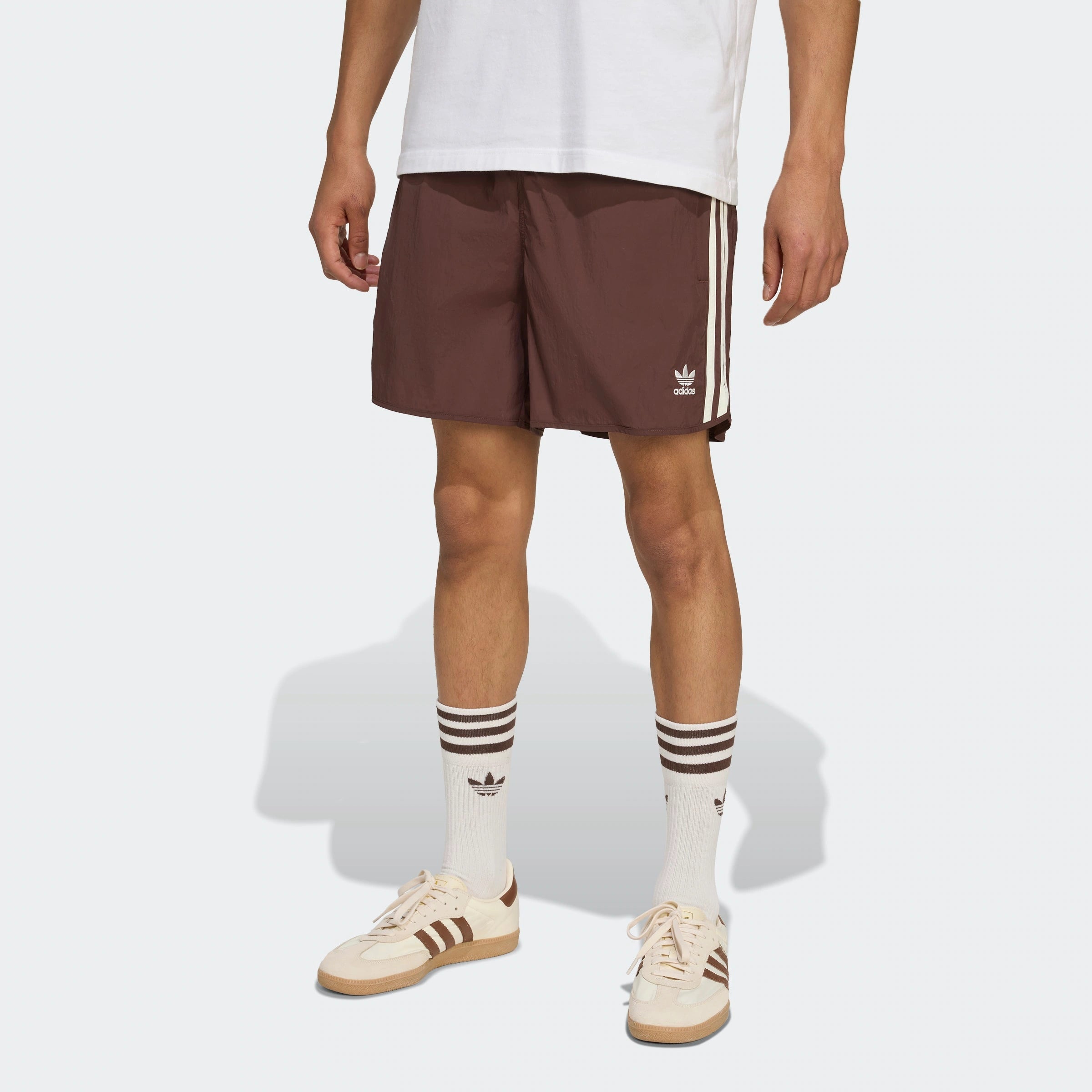 “Adidas Classics Sprinter Shorts – Auburn / Off White. Dunkelbraune Retro-Shorts aus leichtem Material, mit weißen 3-Streifen und gesticktem Logo.“