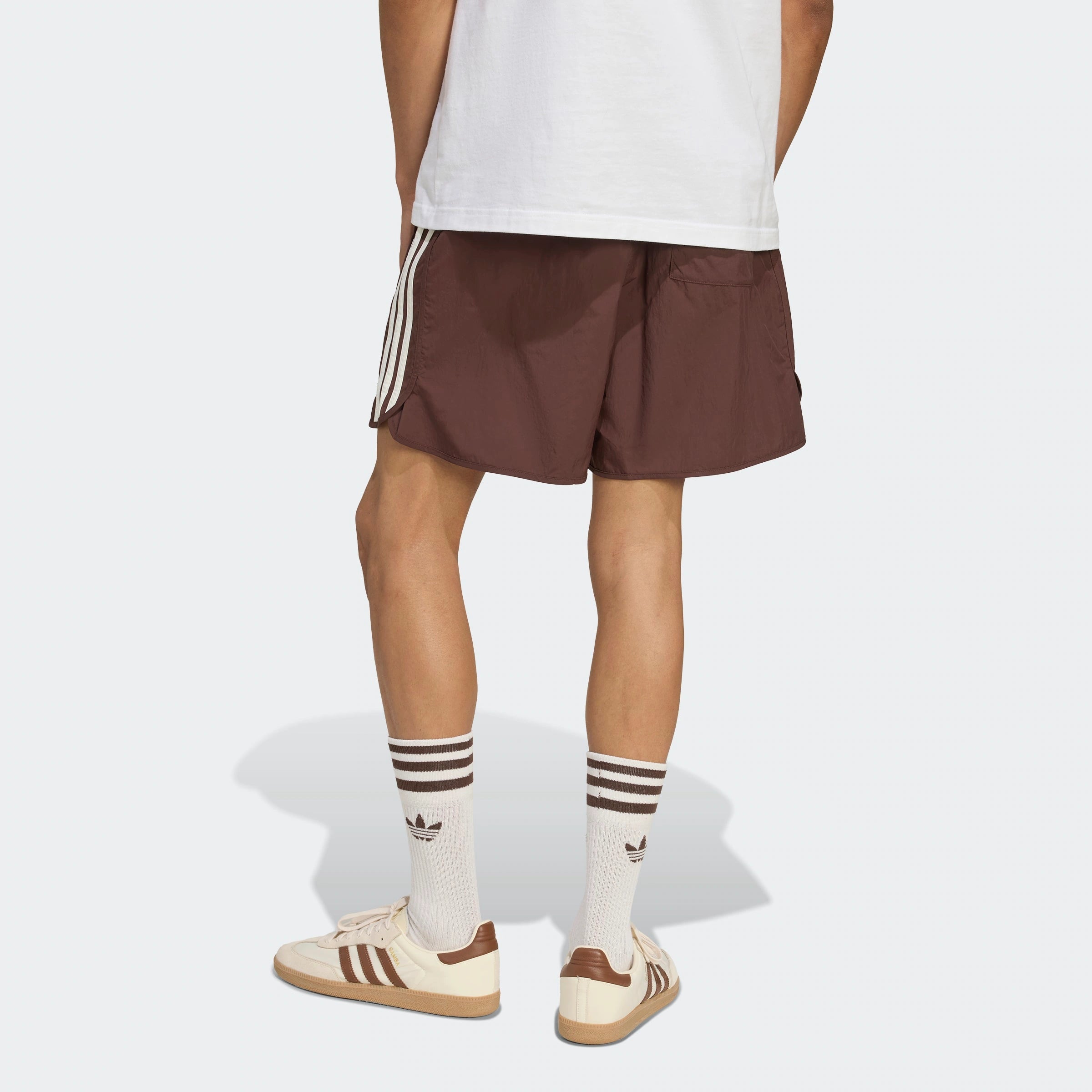 “Adidas Classics Sprinter Shorts – Auburn / Off White. Dunkelbraune Retro-Shorts aus leichtem Material, mit weißen 3-Streifen und gesticktem Logo.“