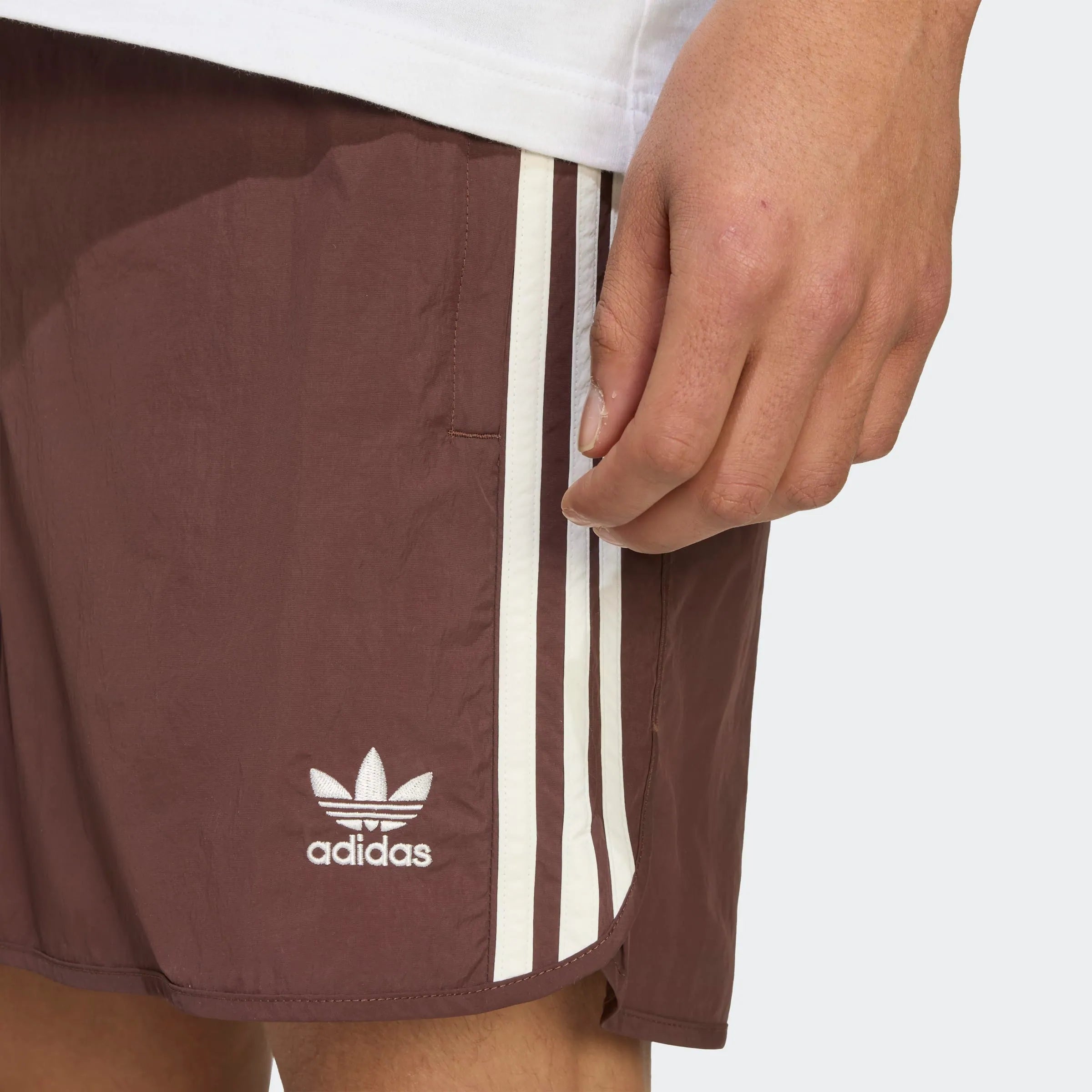 “Adidas Classics Sprinter Shorts – Auburn / Off White. Dunkelbraune Retro-Shorts aus leichtem Material, mit weißen 3-Streifen und gesticktem Logo.“