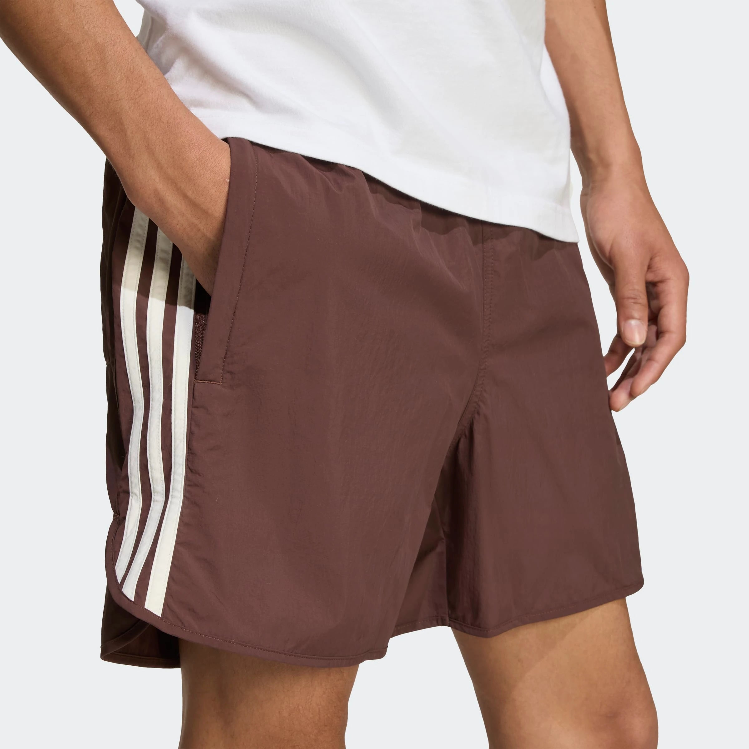 “Adidas Classics Sprinter Shorts – Auburn / Off White. Dunkelbraune Retro-Shorts aus leichtem Material, mit weißen 3-Streifen und gesticktem Logo.“