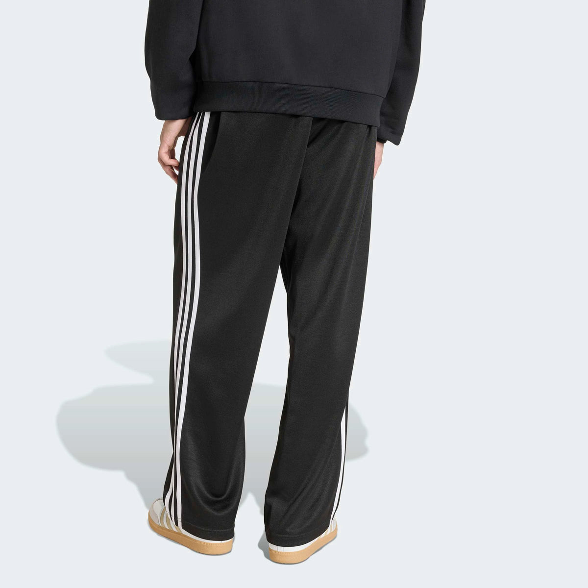 adidas Originals Adicolor Loose Tracksuit Pants in Black – Rueckansicht am Model der schwarzen Trainingshose mit den ikonischen 3-Stripes und lockerem Schnitt.
