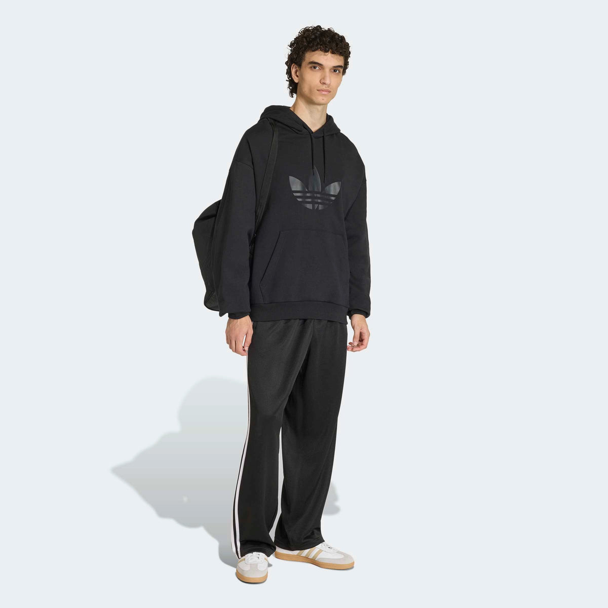 adidas Originals Adicolor Loose Tracksuit Pants in Black – Vorderansicht Outfit am Model der schwarzen Trainingshose mit den ikonischen 3-Stripes und lockerem Schnitt.