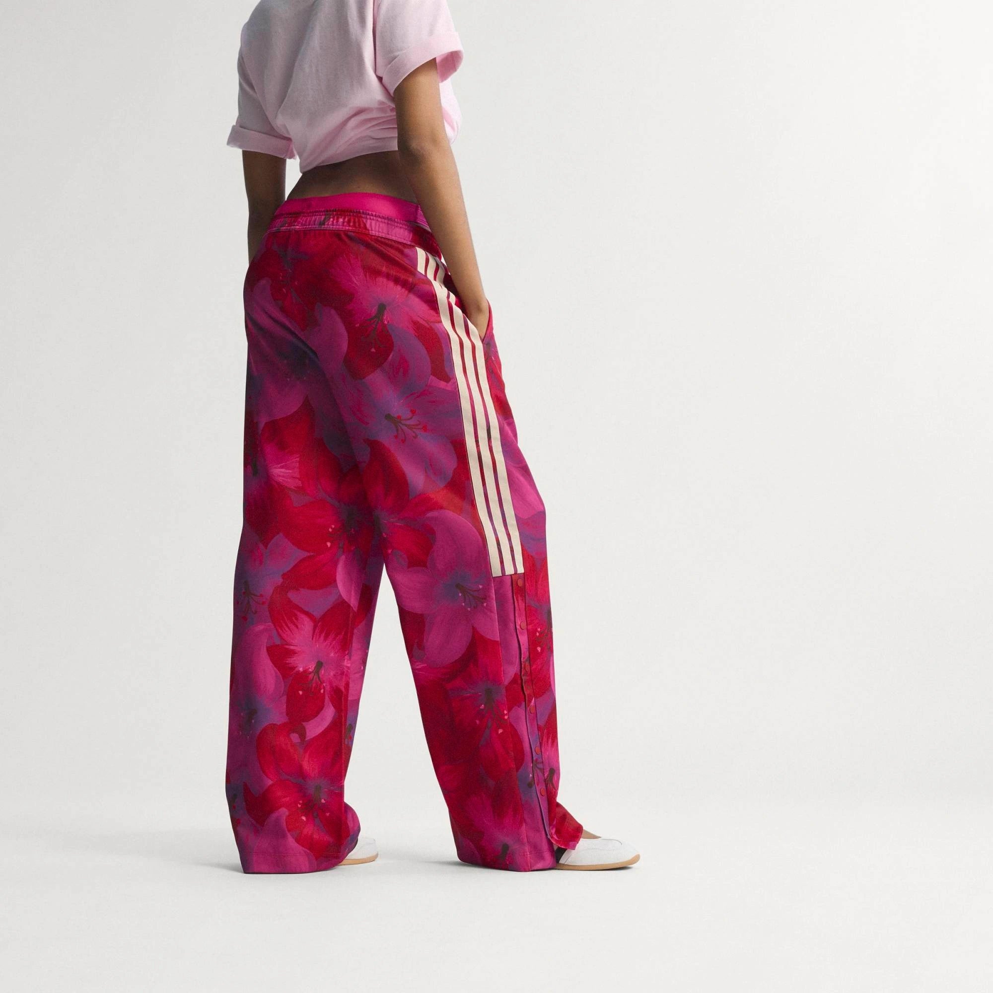 „Frauen adidas x Farm Rio Tiro Trainingshose in Bahia Magenta und Rot mit tropischem Blumenmuster an den Seiten und weißen 3-Streifen bei Stickabush Berlin.“